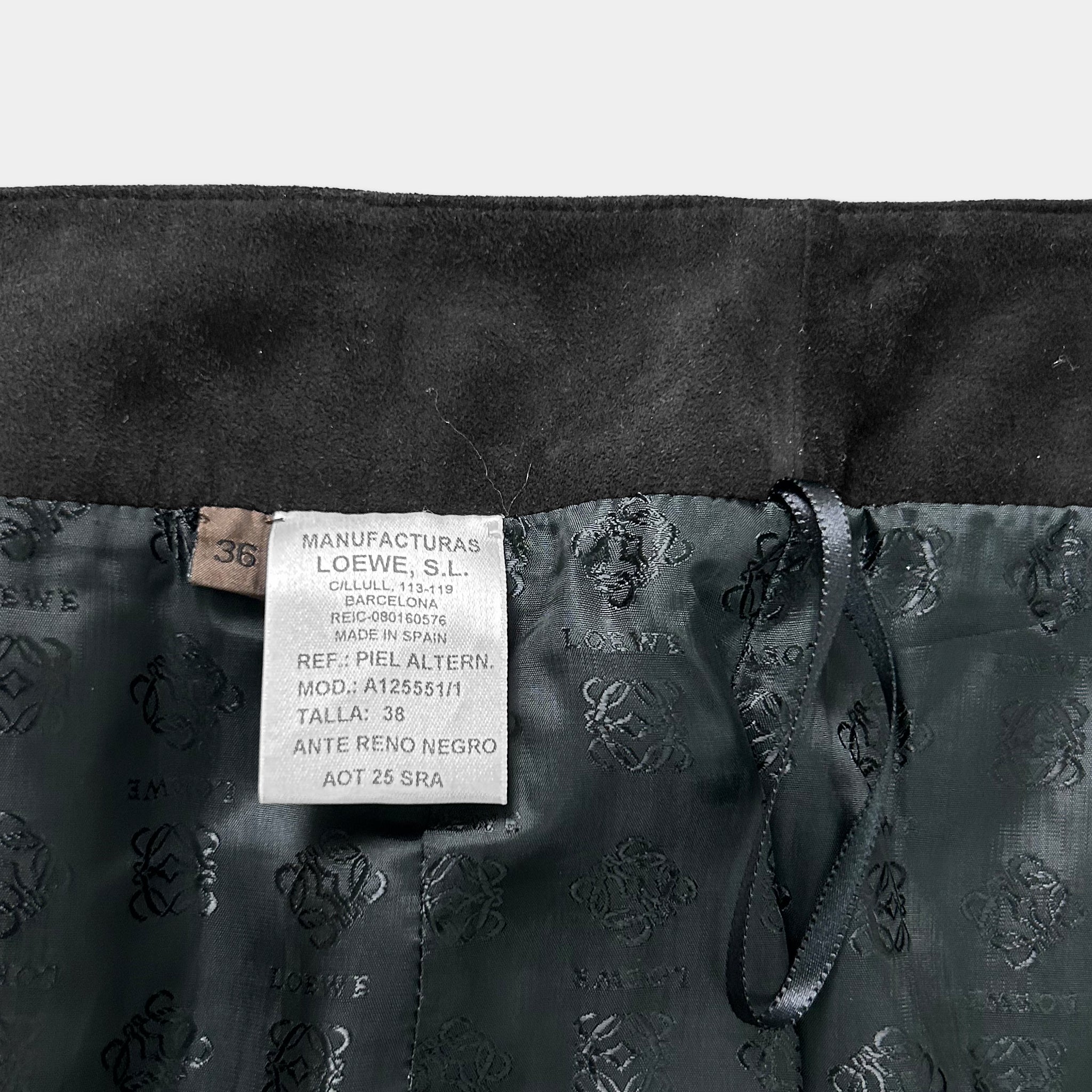 a close-up view of a label attached to a black fabric, likely a piece of clothing. The label appears to contain information about the product, such as the manufacturer, product number, and other details.