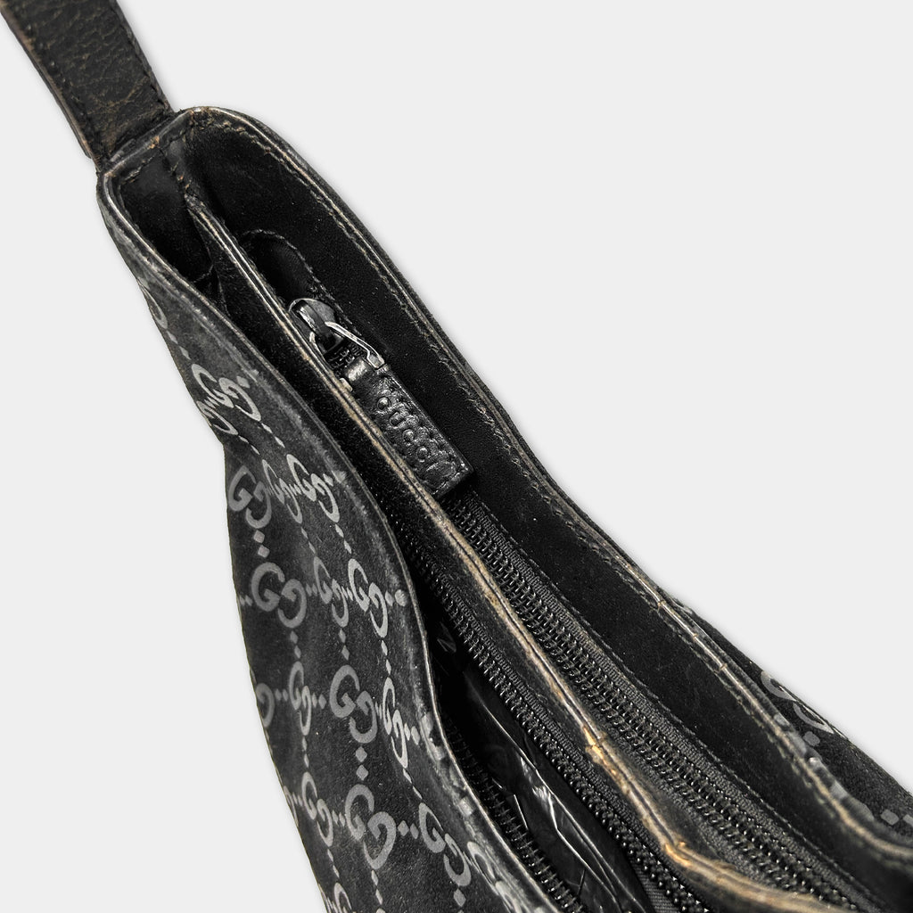 A close-up view of a black Gucci handbag with a distinctive white pattern.