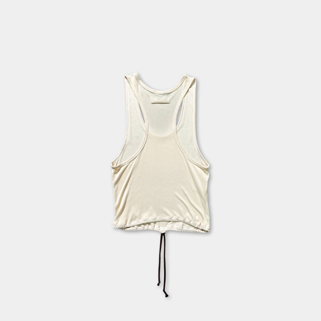 A white sleeveless top with a drawstring waist and a black tie at the bottom is shown against a plain white background.