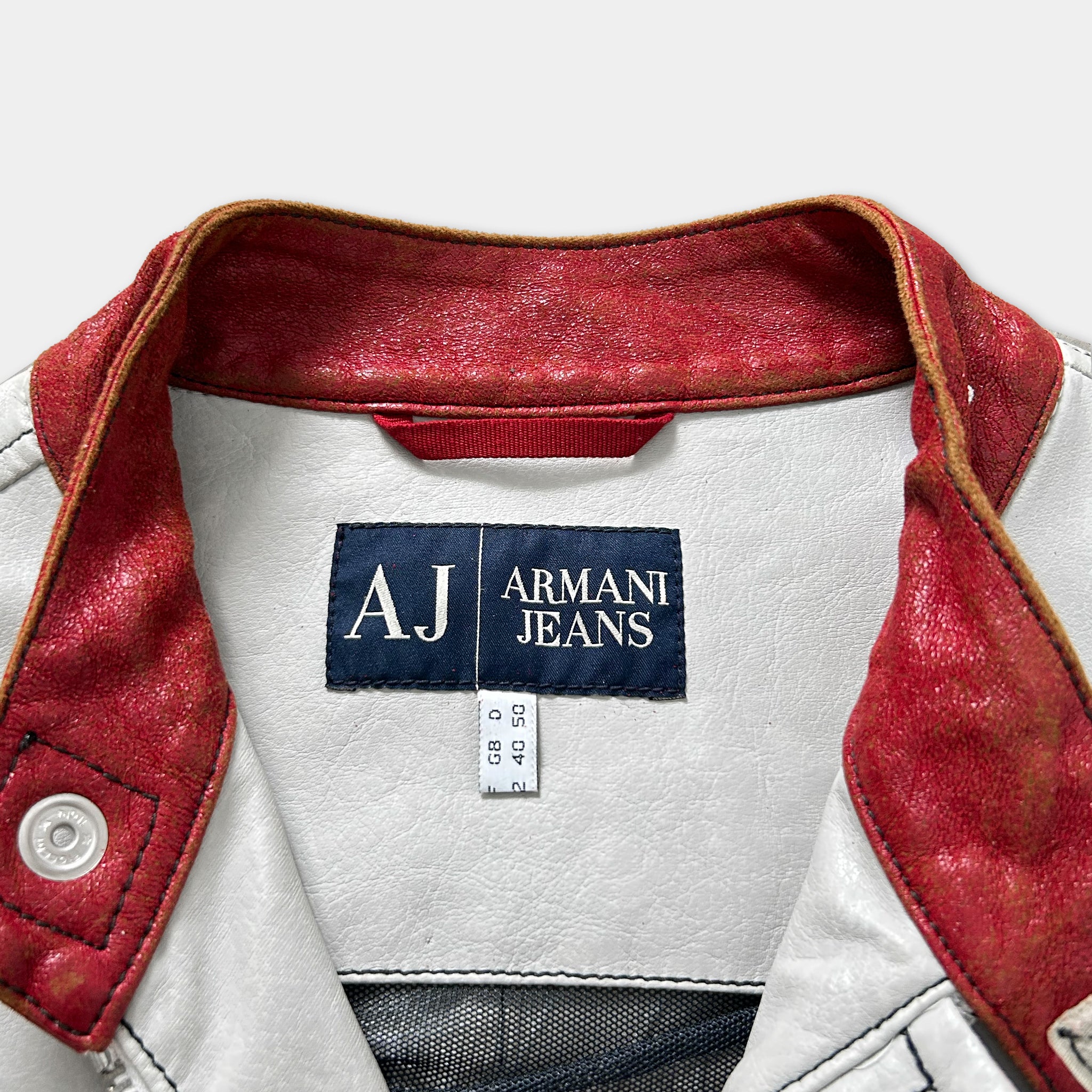 a close-up view of a white and red jacket with a red collar and a label on the back, indicating the brand and size of the jacket.