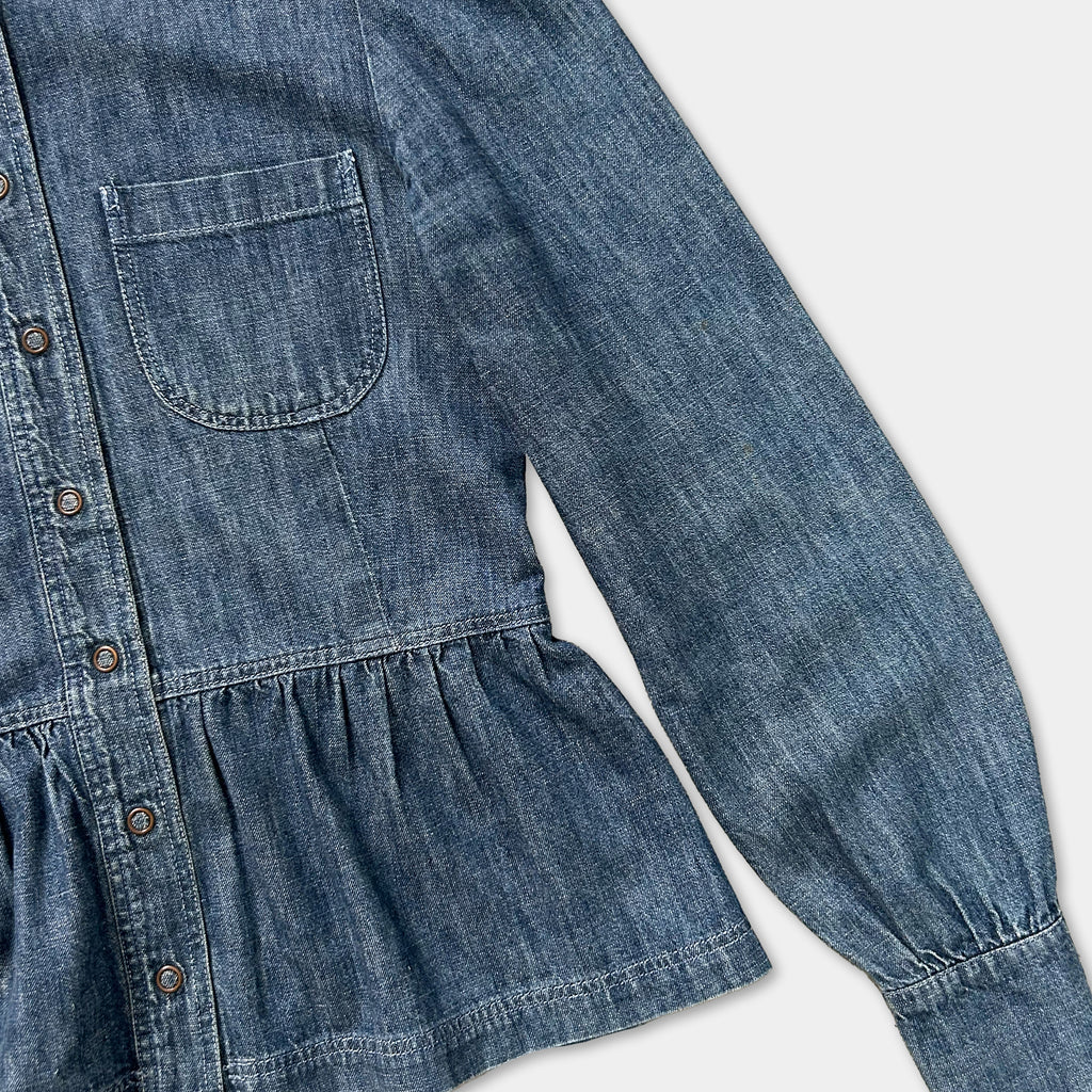 A close-up view of a denim jacket with a ruffled collar and puffed sleeves.