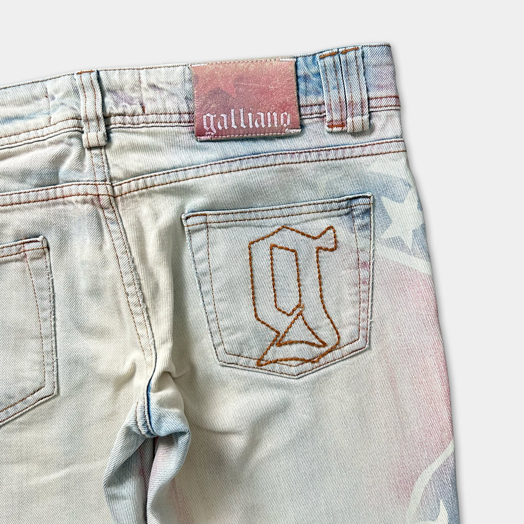A pair of light blue denim jeans with a pink and blue patterned design on the back pocket.