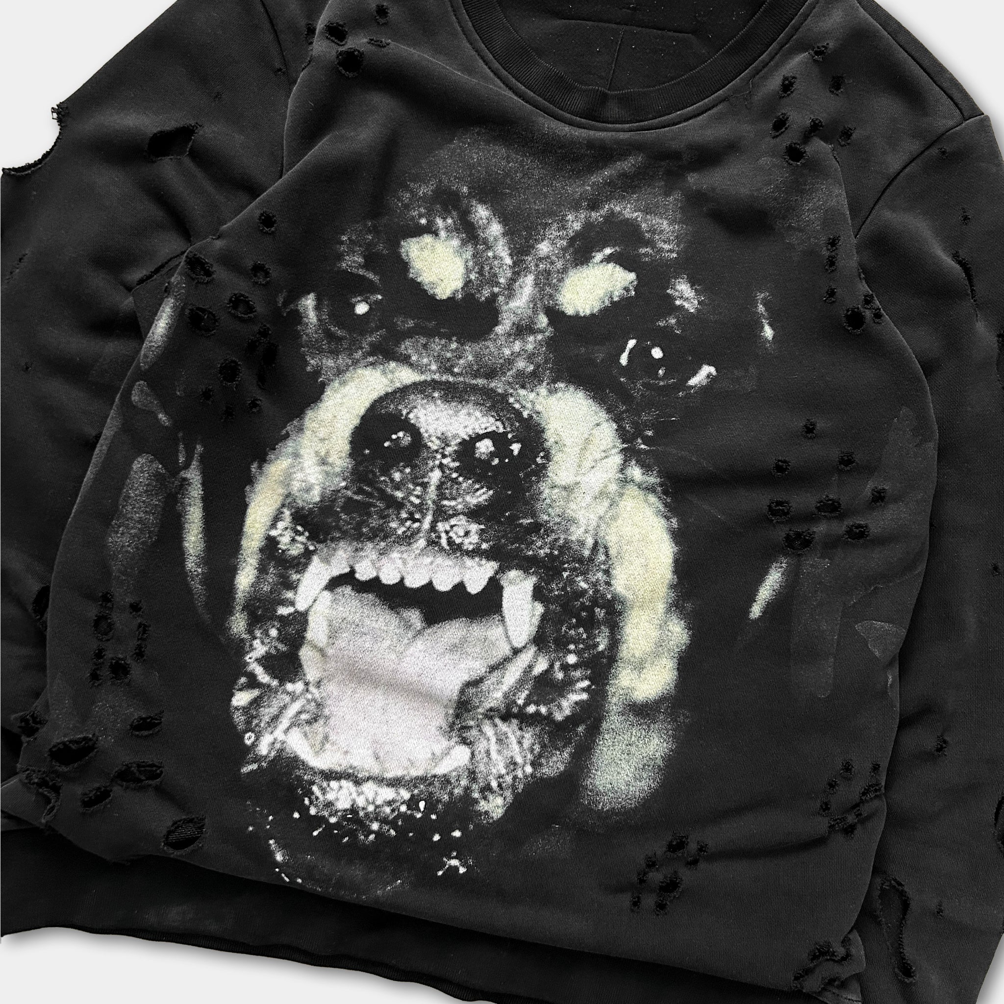 A close-up of a black and white image of a dog's face with its mouth open, giving the impression of a snarling or growling expression.