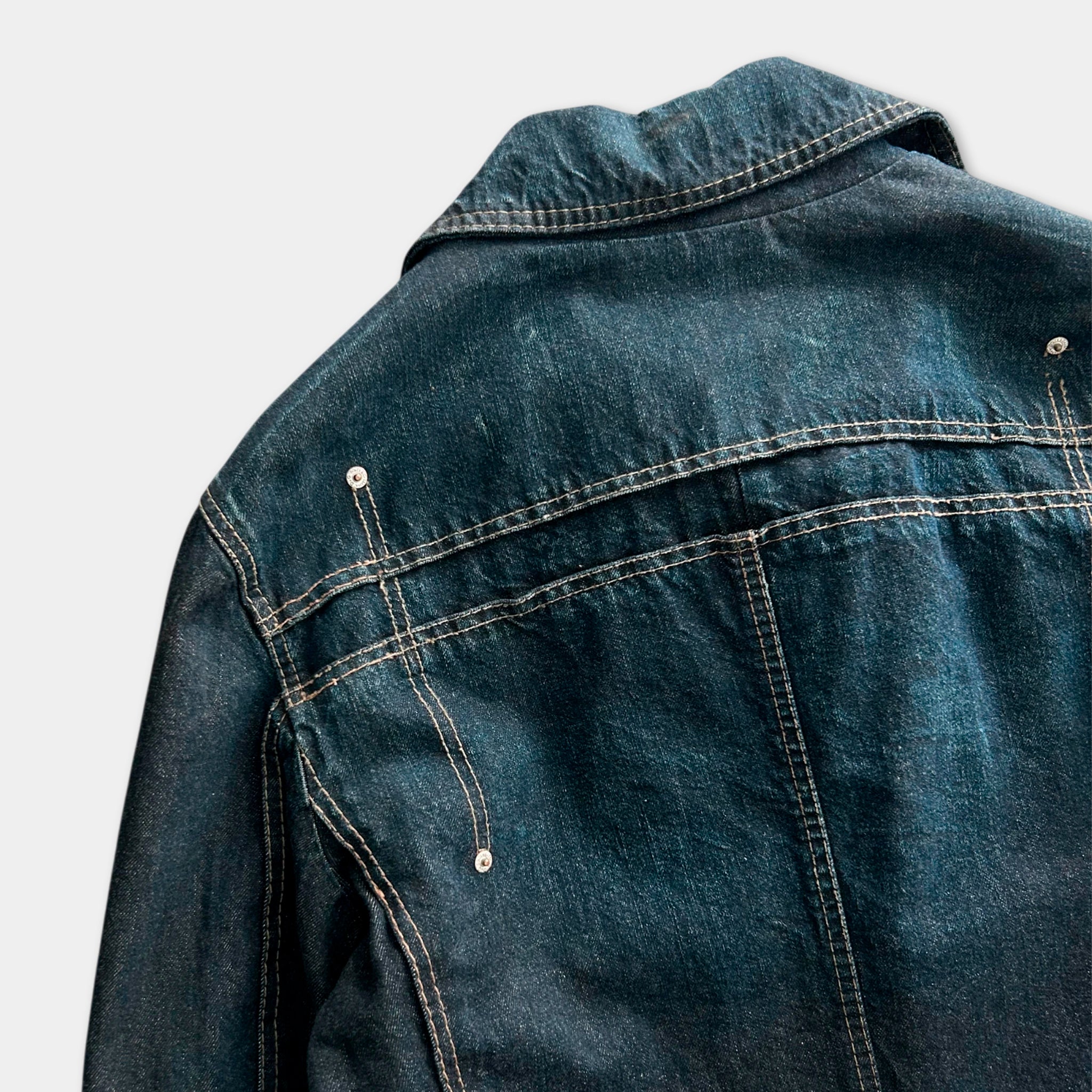 the back of a blue denim jacket with a zipper and pockets.