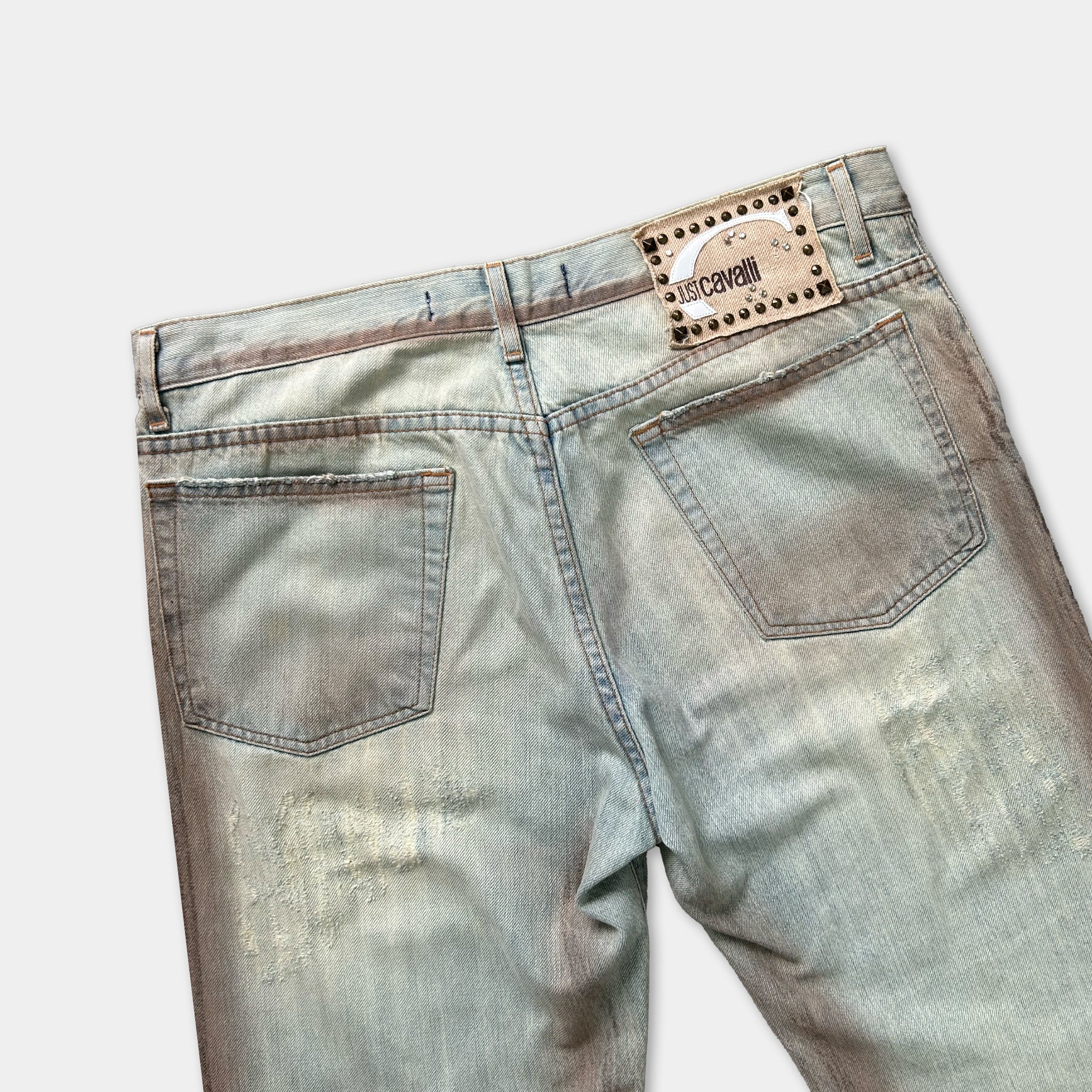 A pair of well-worn, faded denim jeans with visible wear and tear.