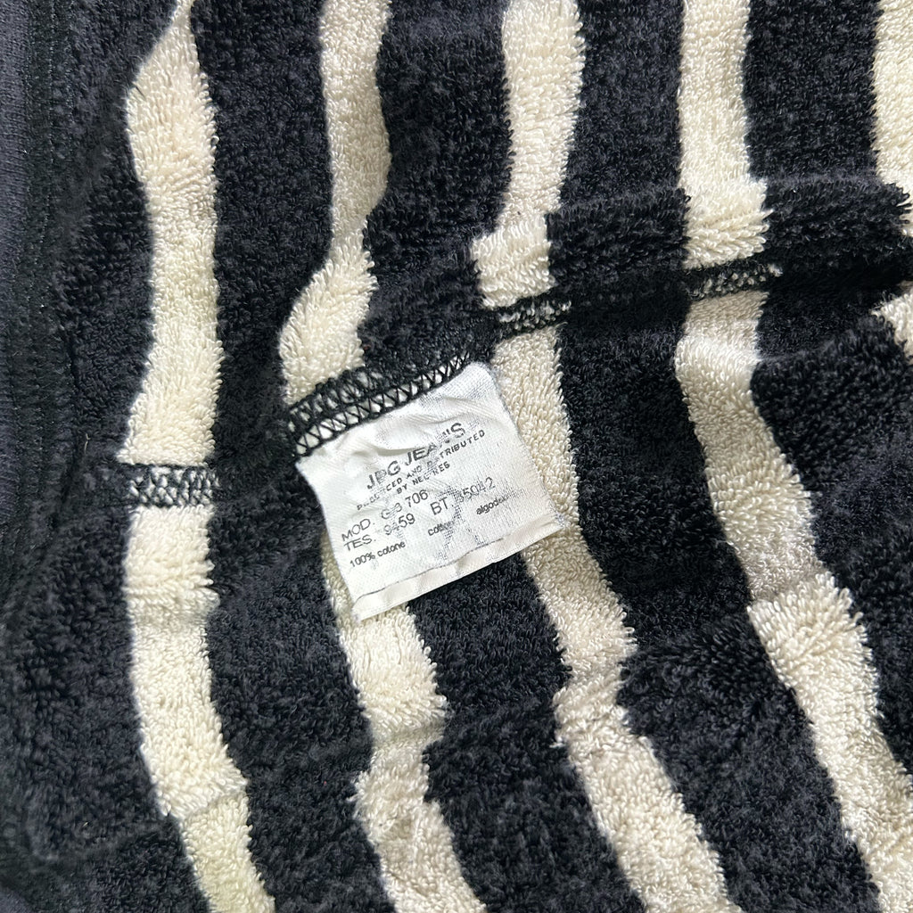 a close-up view of a black and white striped fabric, possibly a towel or bath mat, with a small white label attached to it.
