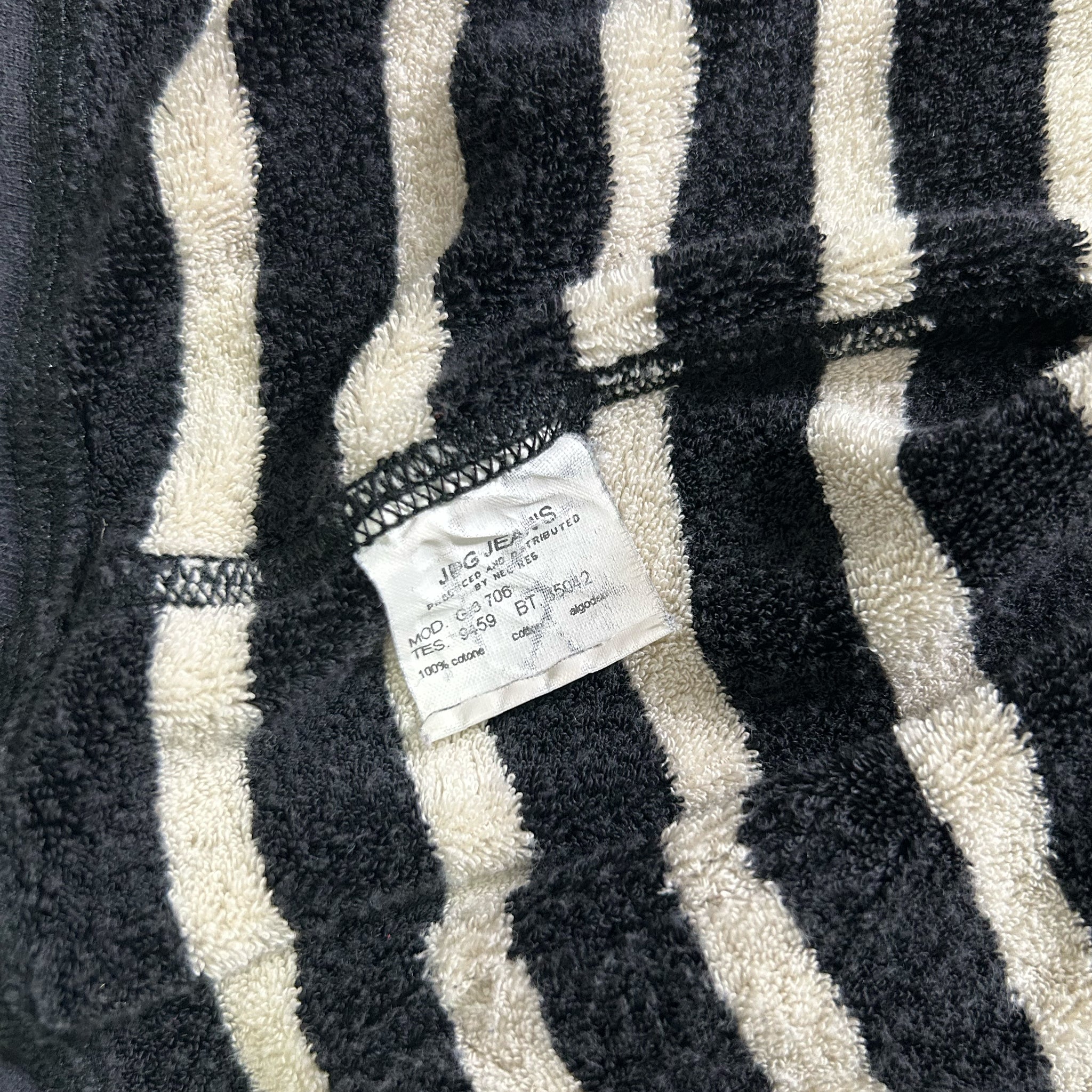 a close-up view of a black and white striped fabric, possibly a towel or bath mat, with a small white label attached to it.