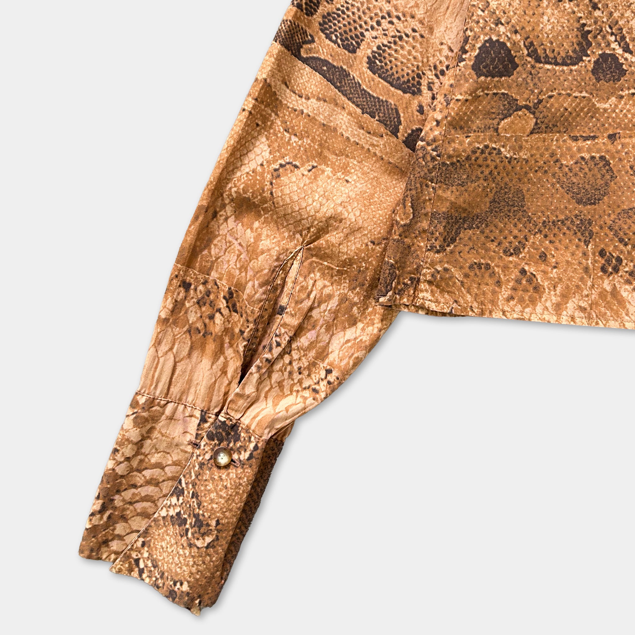 a close-up view of a brown, patterned fabric, possibly a piece of clothing or a textile, with a distinctive snake skin-like design.