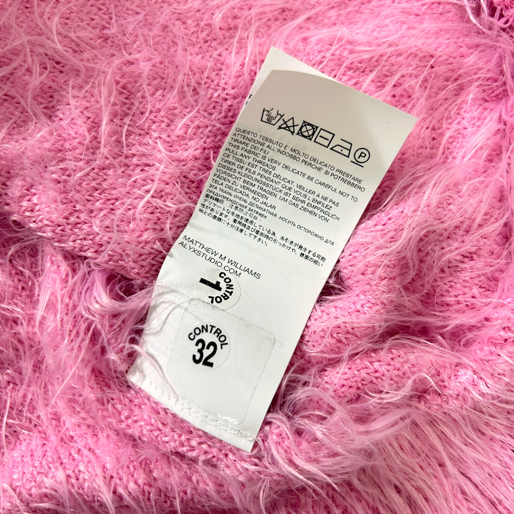 a white label with text and symbols, placed on a pink fuzzy fabric.