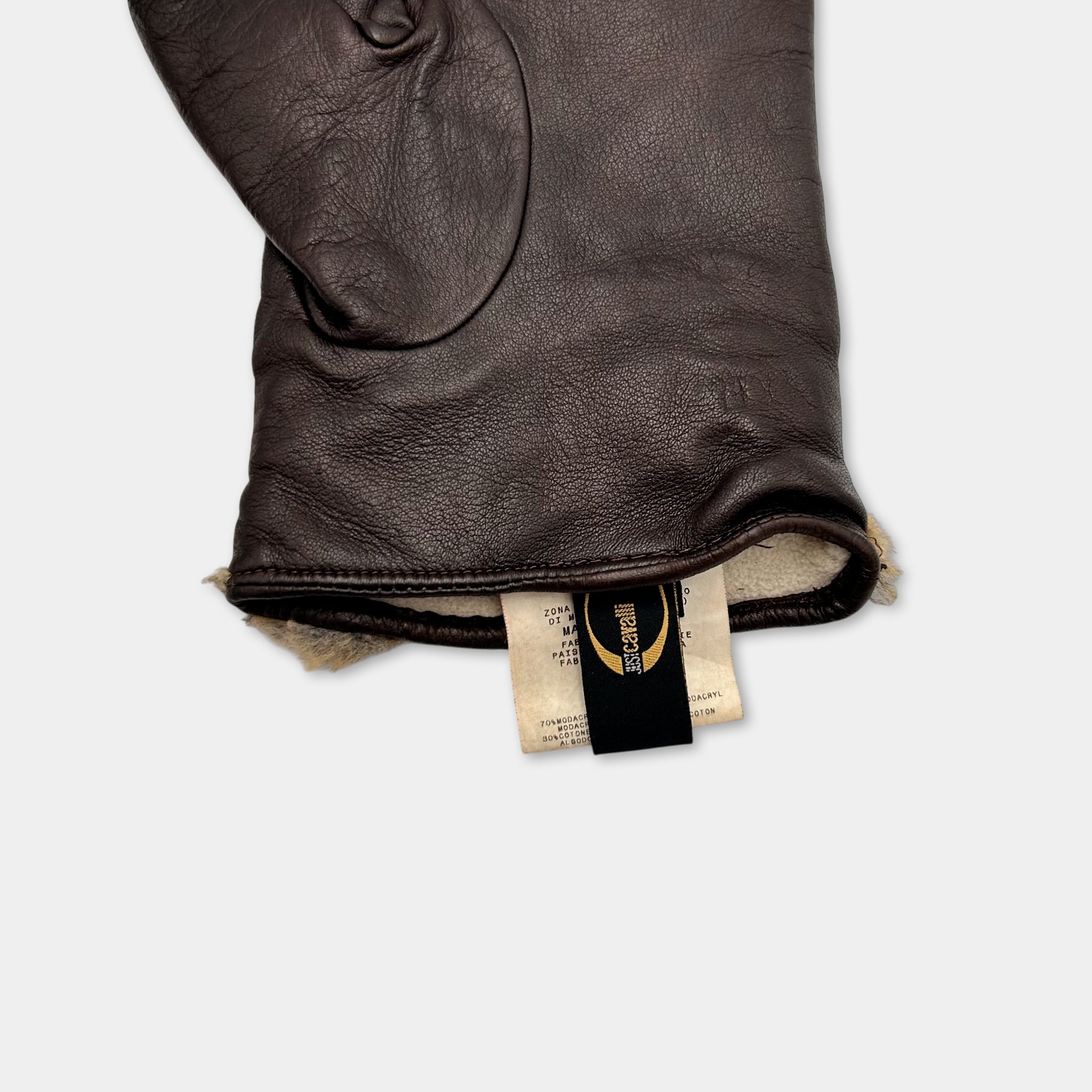 A close-up view of a brown leather glove with a label attached to it.