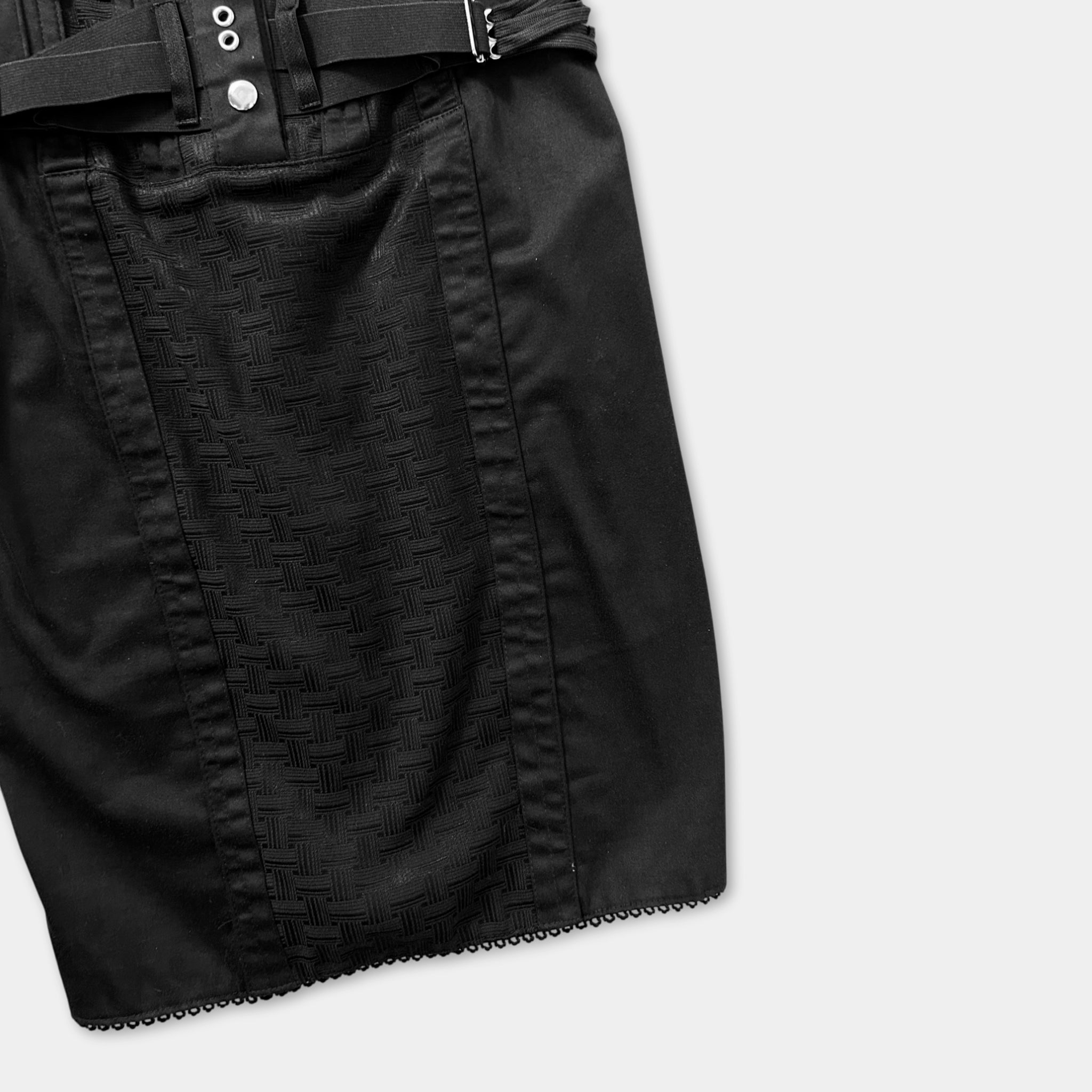 A black skirt with a belt and a patterned design on the fabric.