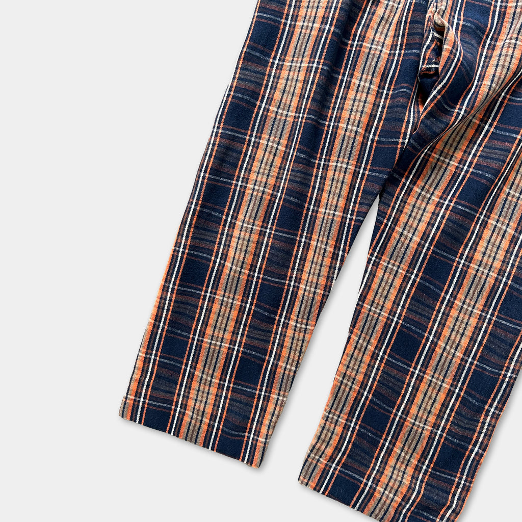 A pair of plaid pants with a striped pattern in shades of blue, orange, and white.