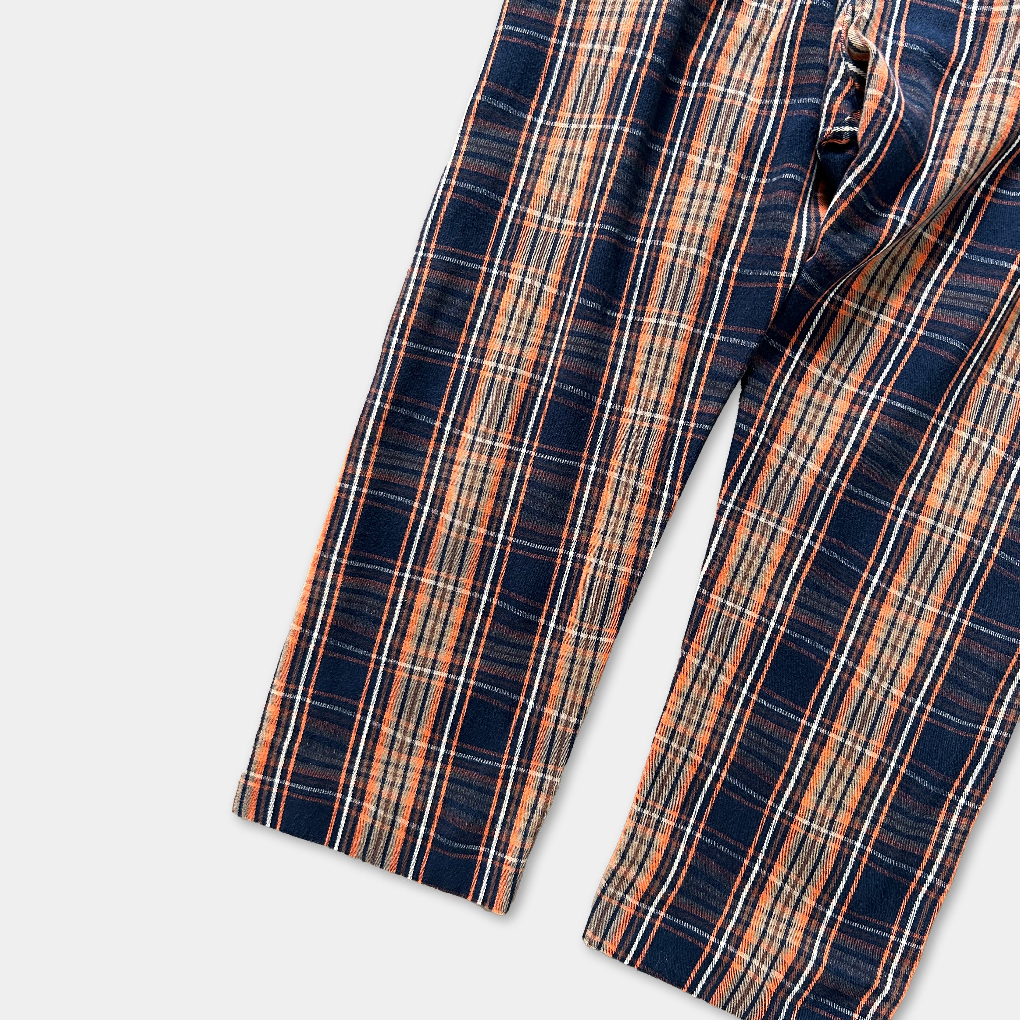 A pair of plaid pants with a striped pattern in shades of blue, orange, and white.