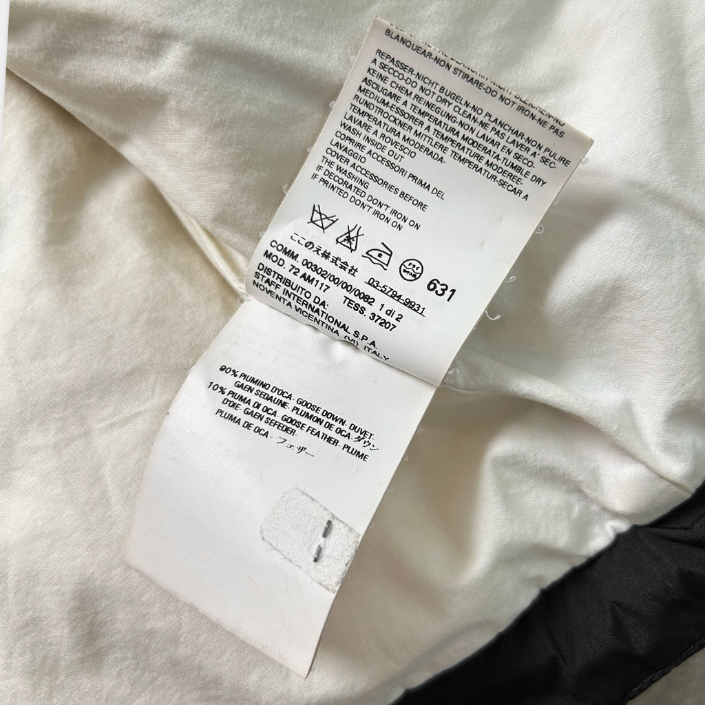 a close-up view of a white fabric, possibly a piece of clothing, with a label attached to it. The label contains text and symbols, but the image does not contain any text that can be transcribed.