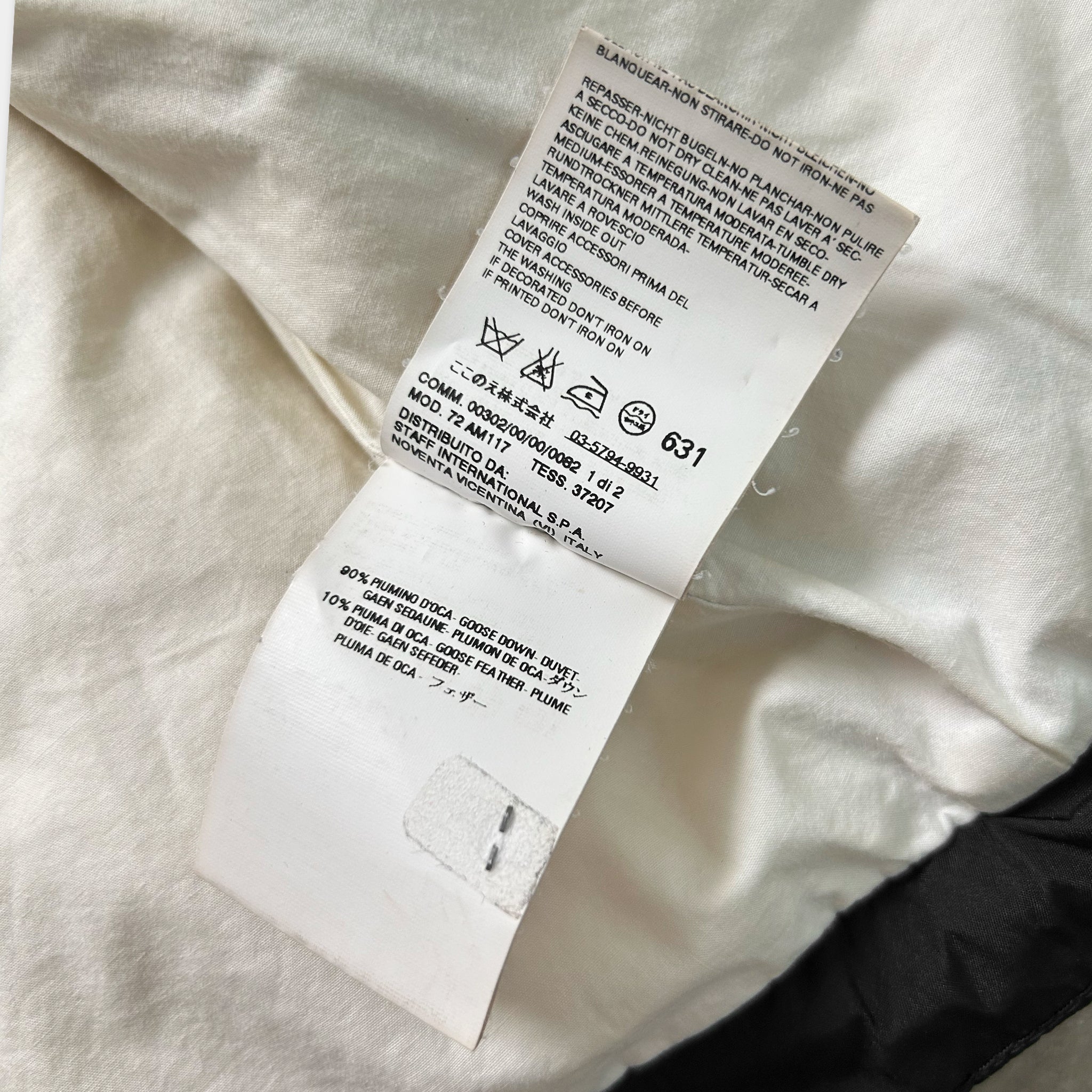 a close-up view of a white fabric, possibly a piece of clothing, with a label attached to it. The label contains text and symbols, but the image does not contain any text that can be transcribed.
