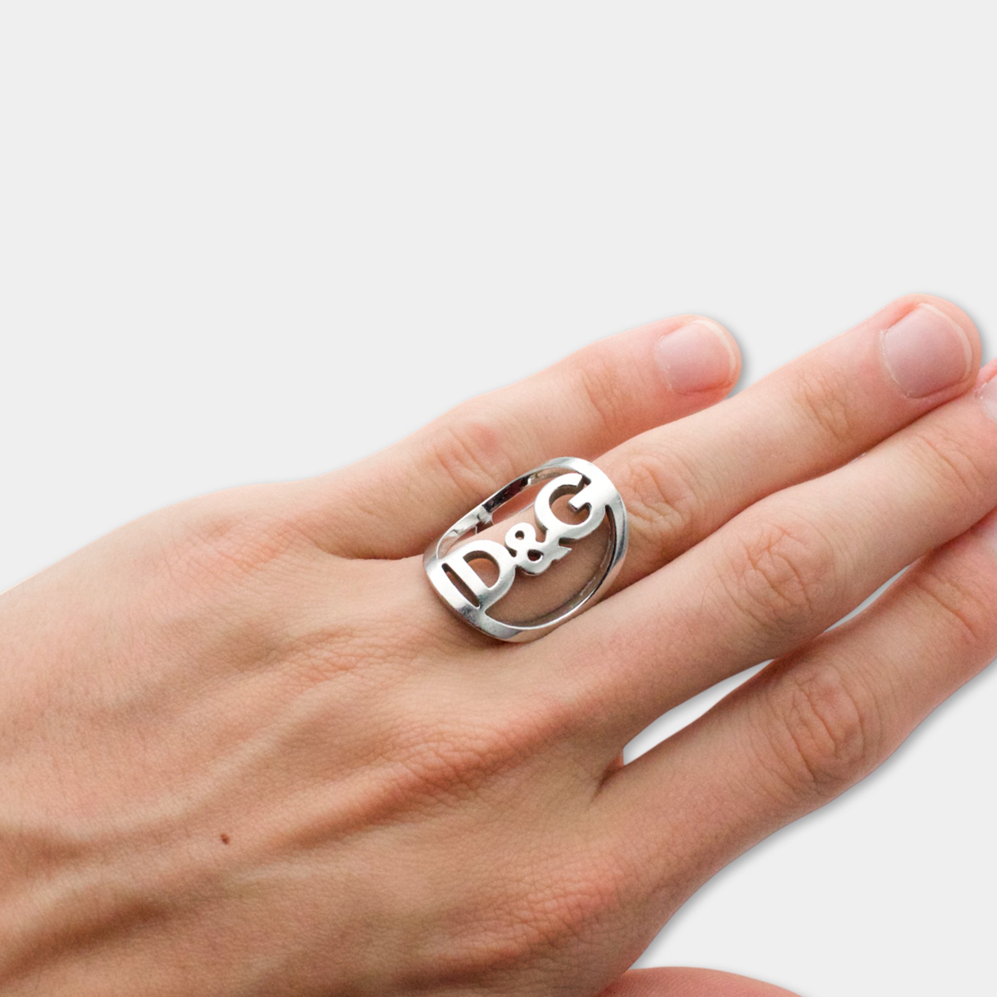A close-up of a person's hand wearing a ring with the letters 'D&G' engraved on it.