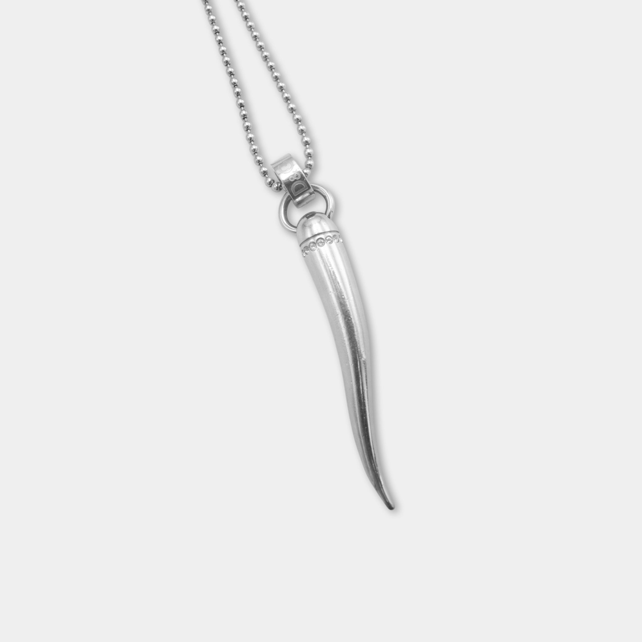 A silver necklace with a pendant featuring a long, curved object resembling a horn or a similar shape.