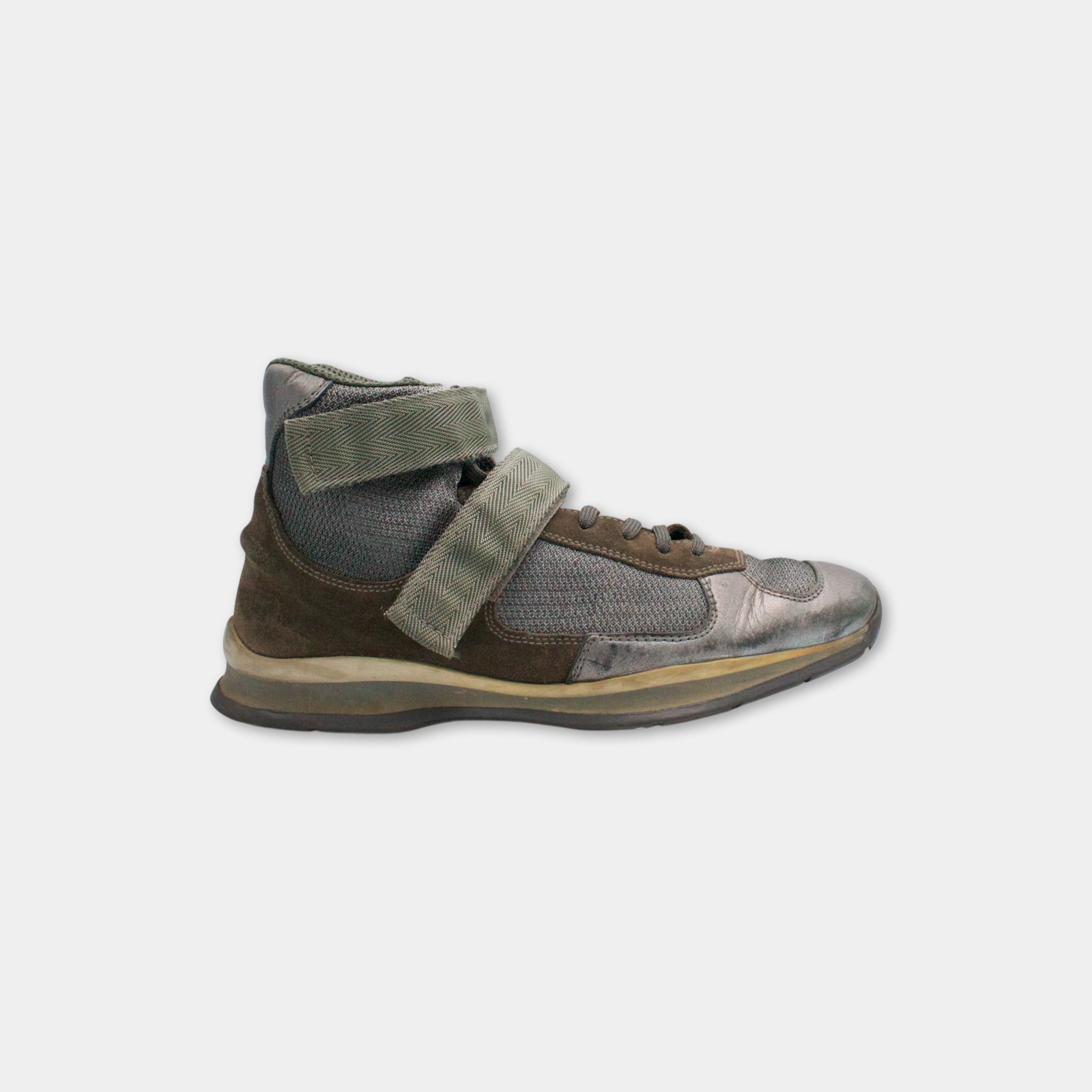 A single, worn high-top sneaker with a mesh upper and a brown leather upper, featuring a high-top design and a strap across the top.