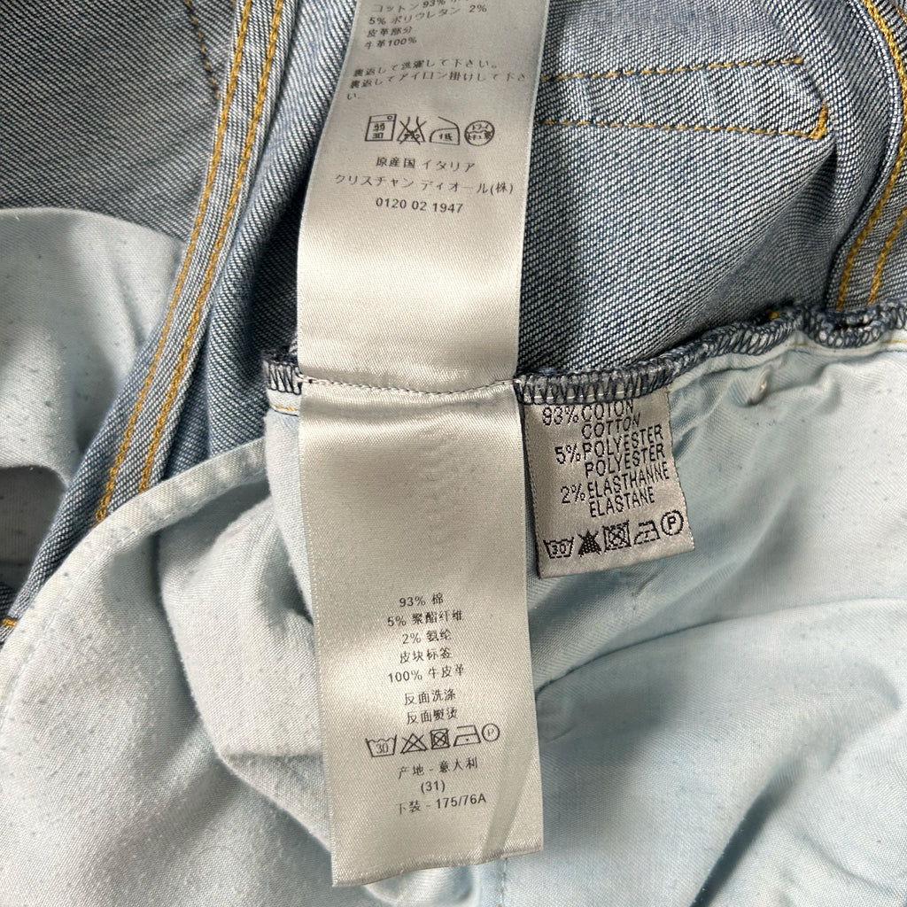 a close-up view of a denim fabric, with a label attached to it. The label contains text in both English and Japanese, providing information about the fabric, such as the material and care instructions.