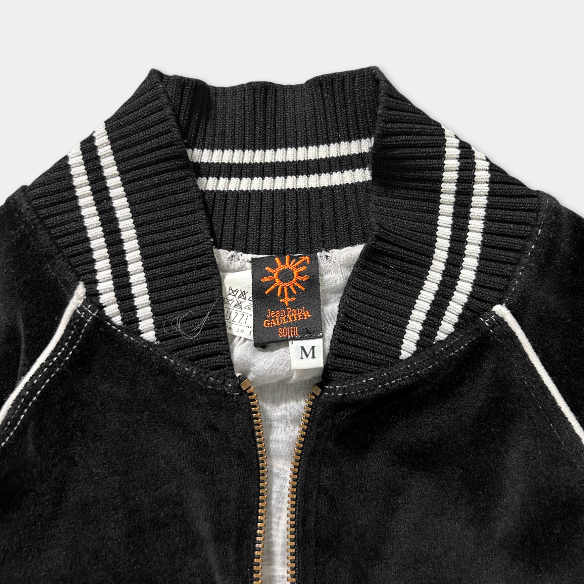A close-up view of a black and white striped jacket with a white collar and zipper.