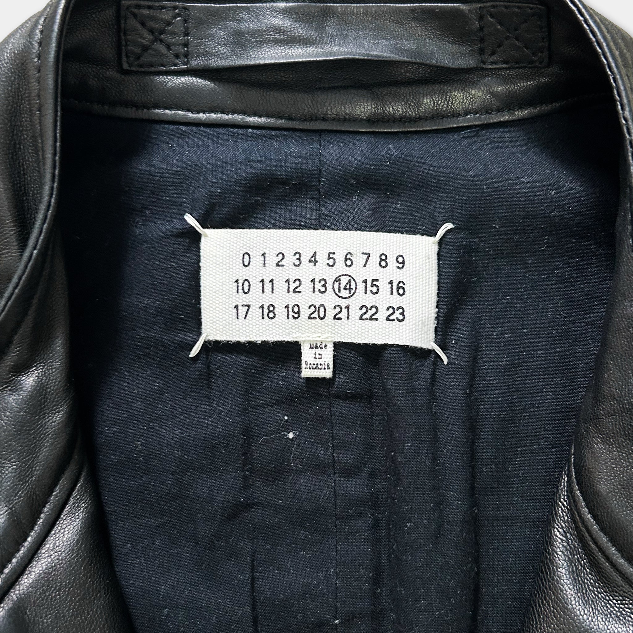 a close-up view of a black leather jacket, focusing on the label on the back.