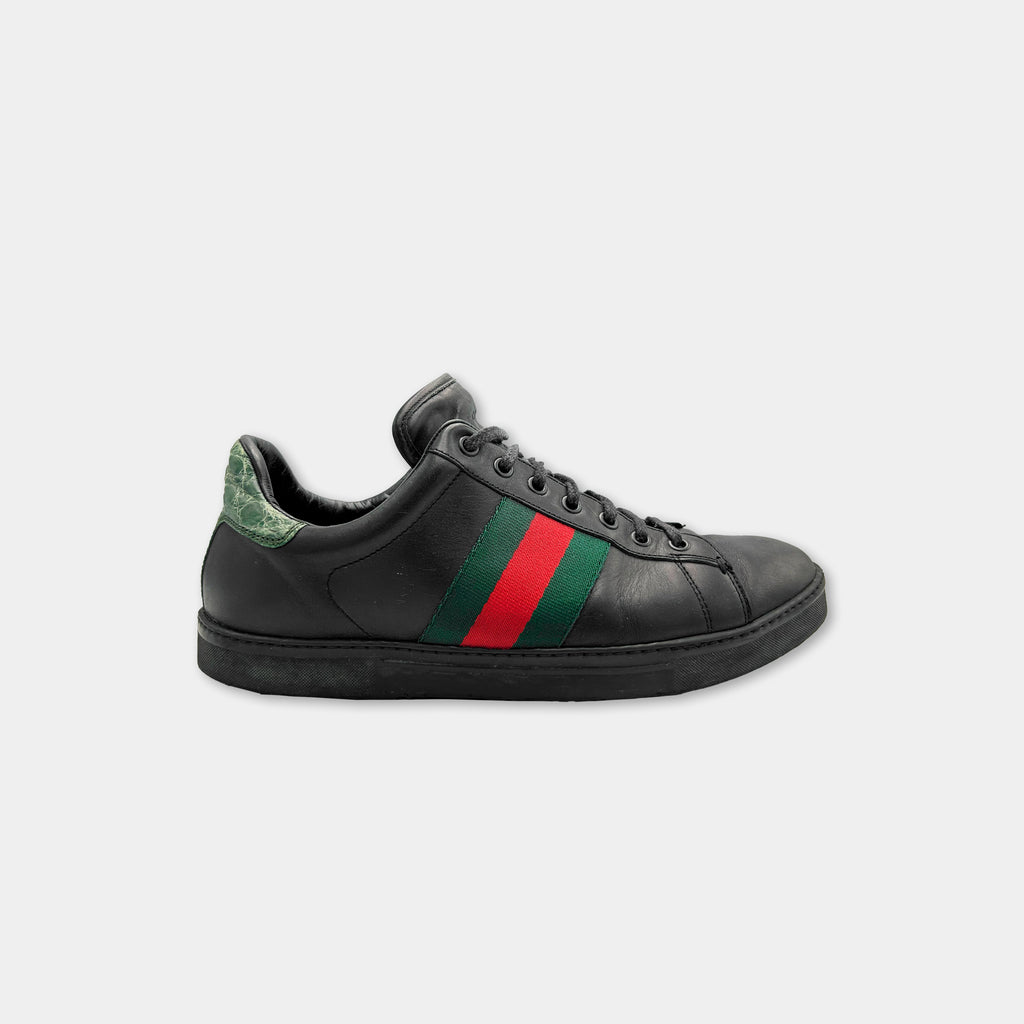 A black Gucci sneaker with a green and red stripe on the side.
