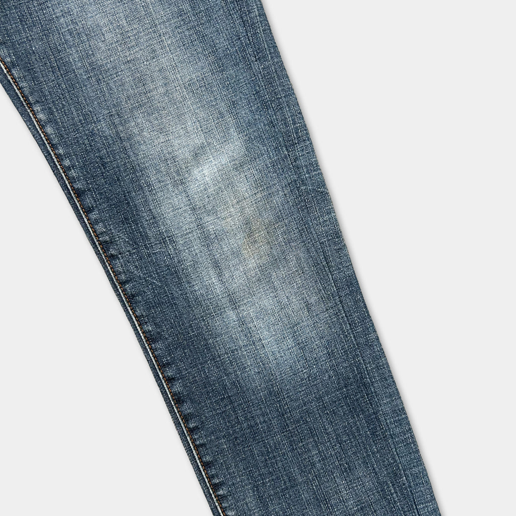 A close-up view of a pair of blue denim jeans, showing the fabric and stitching.