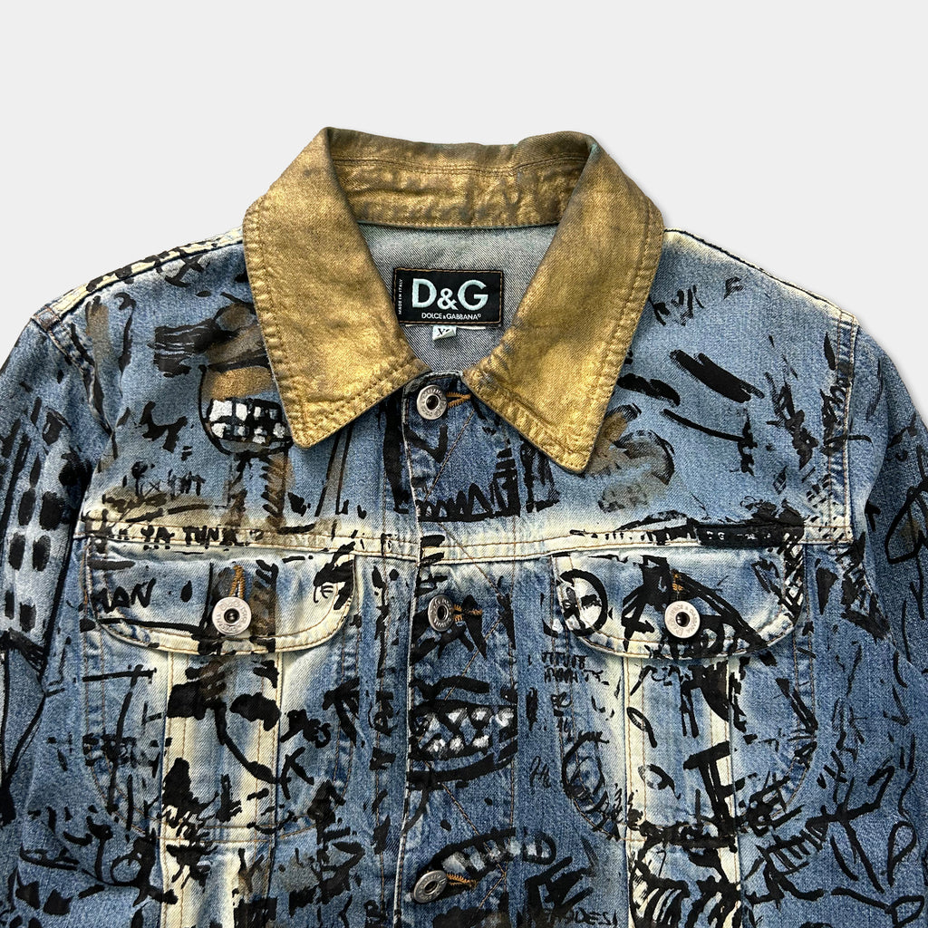 a close-up view of a denim jacket with a distinctive collar and various patterns and designs printed on the fabric.