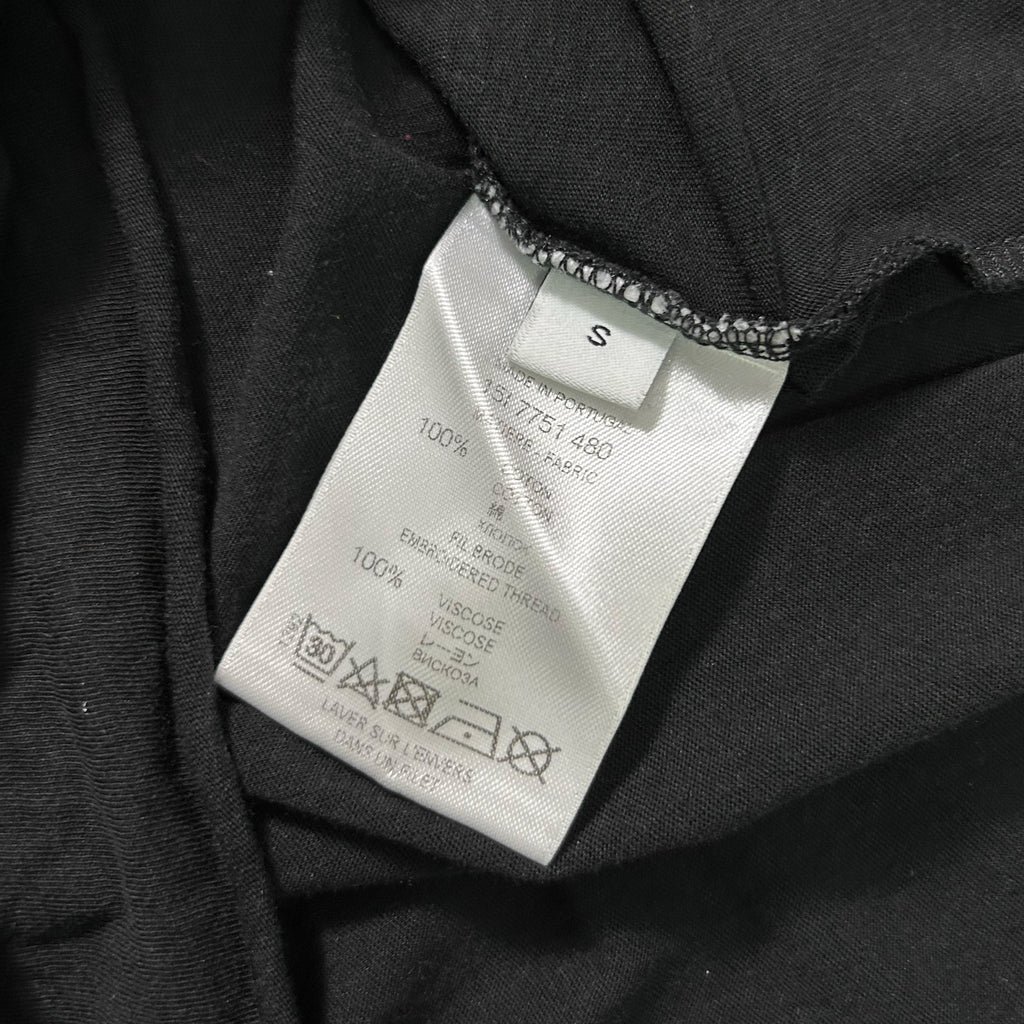 a close-up view of a black fabric, possibly a garment or textile, with a white label attached to it. The label contains text and symbols, likely providing information about the product, such as the brand, material, care instructions, and other relevant details.