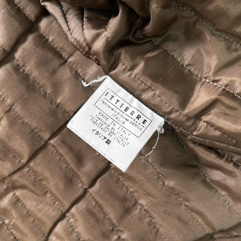 a close-up view of a brown fabric, possibly a piece of clothing or a textile, with a label attached to it. The label appears to be a label or tag, providing information about the product or the manufacturer.