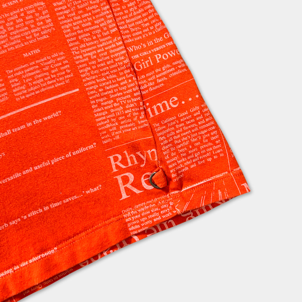 The image is a close-up of a bright orange fabric with a pattern of text and phrases printed on it.