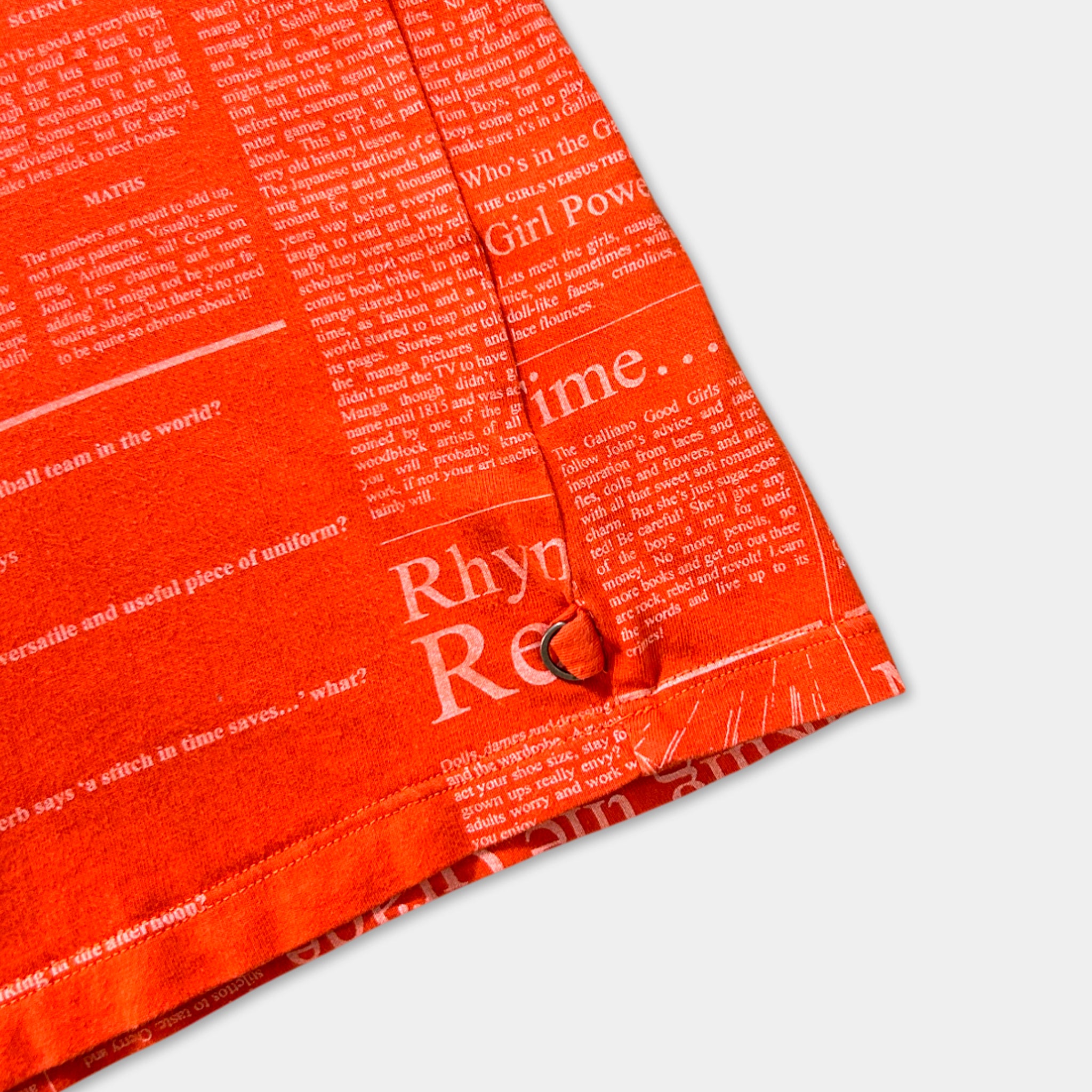 The image is a close-up of a bright orange fabric with a pattern of text and phrases printed on it.
