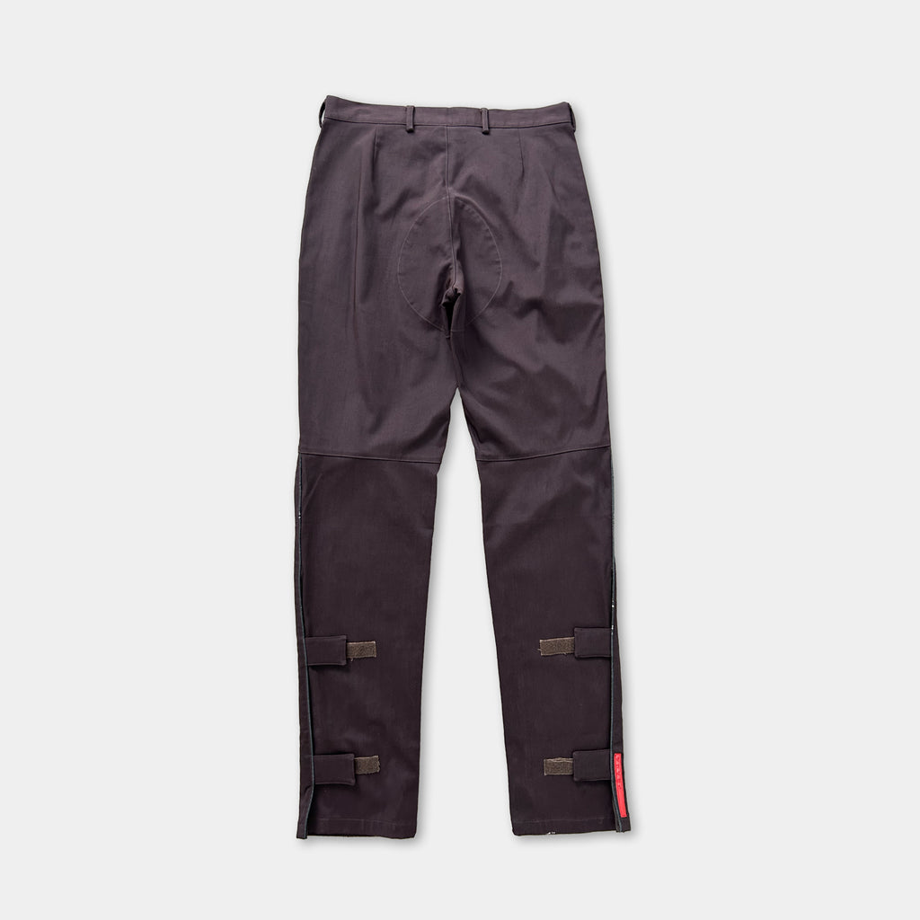 A pair of dark grey pants with a zipper closure and a red tag on the side.