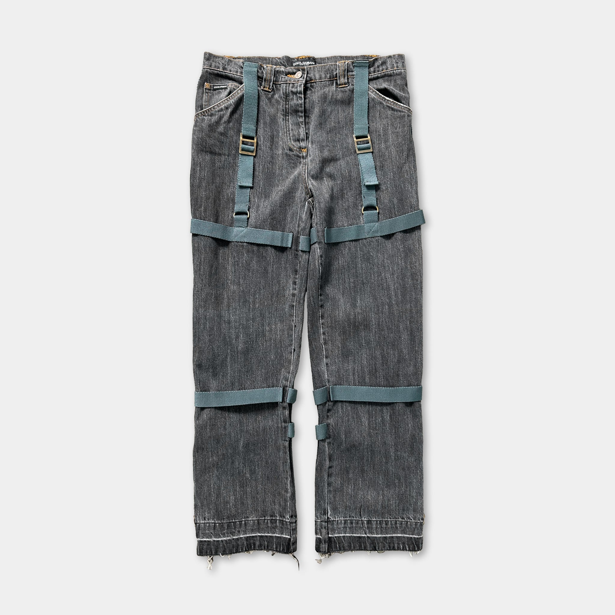 A pair of gray jeans with green straps, which appear to be designed for a unique and unconventional style.