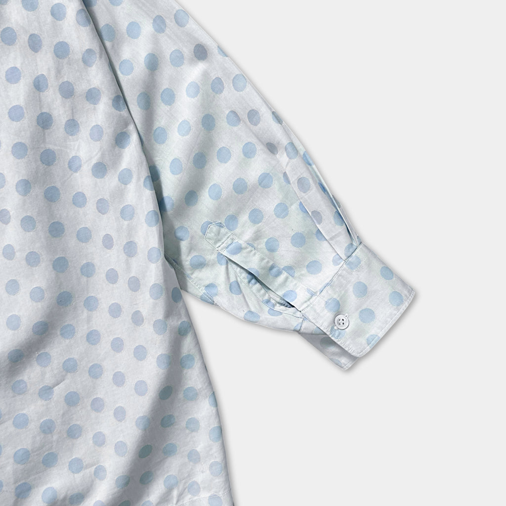 a close-up view of a white shirt with blue polka dots on the sleeve and collar.