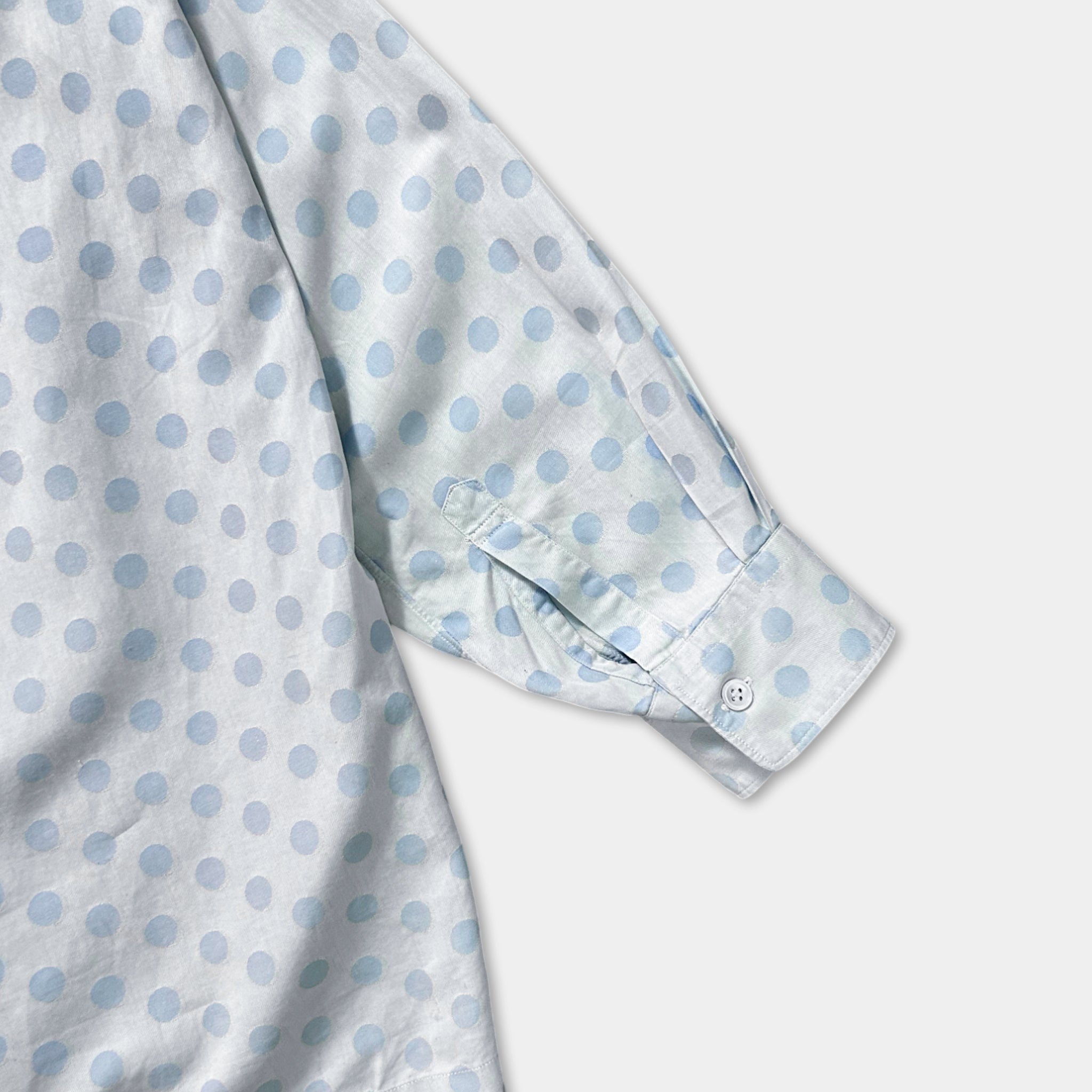 a close-up view of a white shirt with blue polka dots on the sleeve and collar.