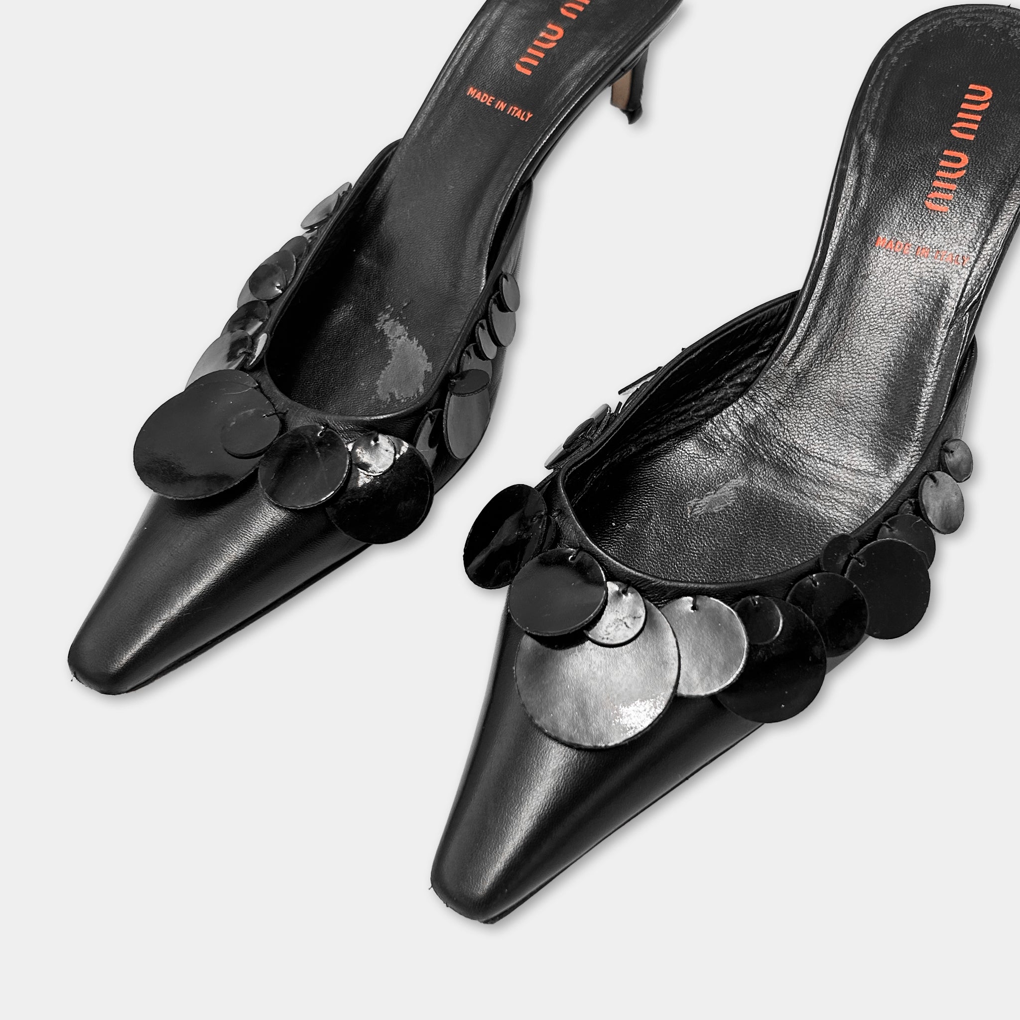 A pair of black leather heeled shoes with metallic sequins on the toe and heel.