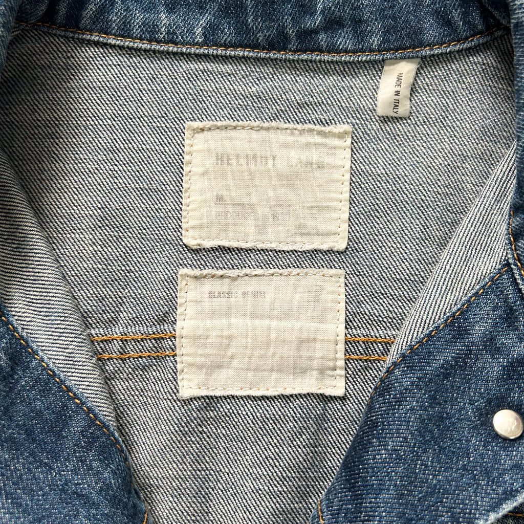 the back of a denim jacket with two white labels attached to the collar.