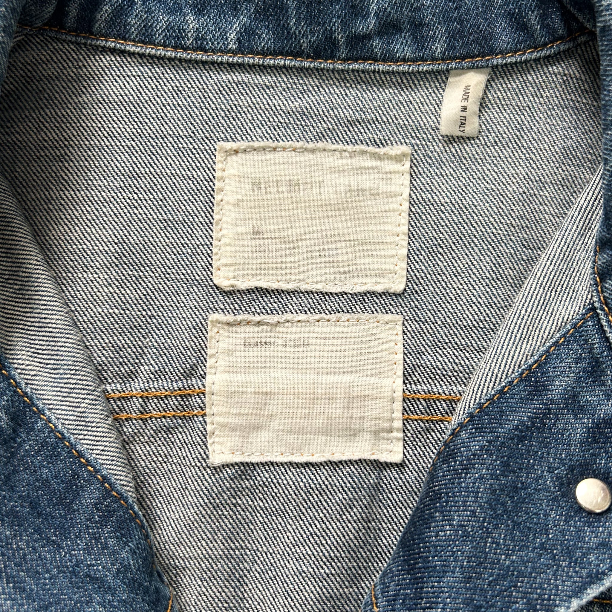 the back of a denim jacket with two white labels attached to the collar.