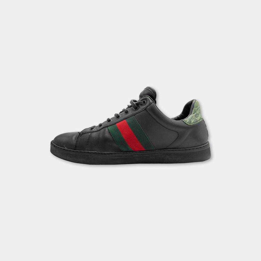 A black Gucci sneaker with a red and green stripe on the side.