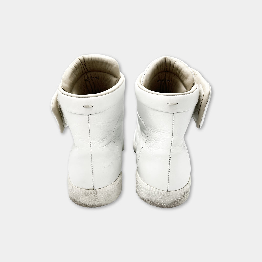 A pair of white leather sneakers with a distinctive design.