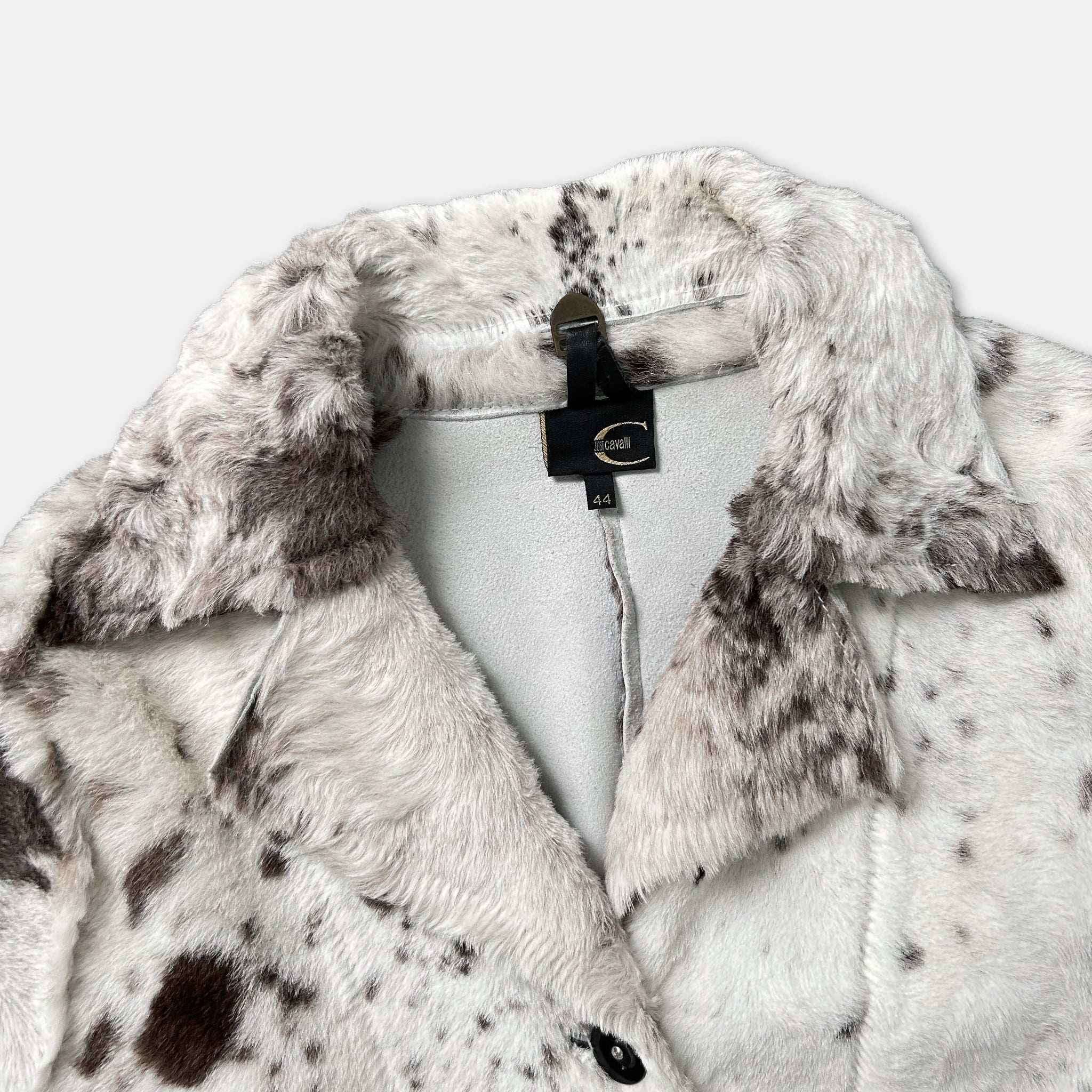 A close-up view of a white fur coat with a black collar and a black tag.