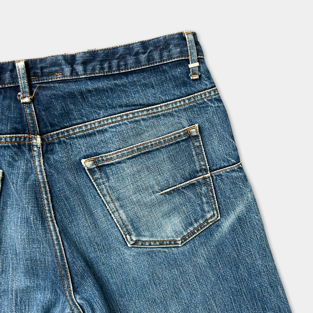 A close-up view of a pair of blue jeans with a pocket and zipper detail.