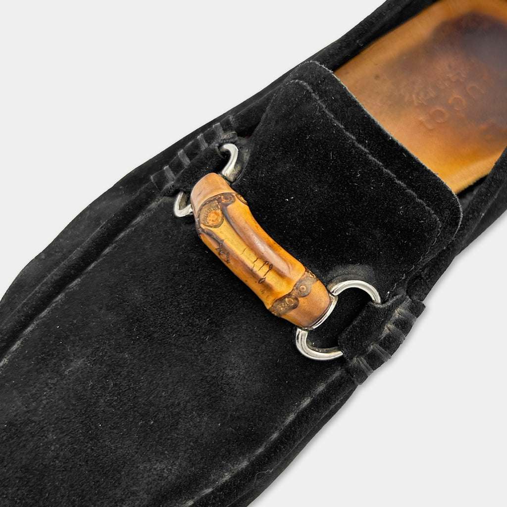 A close-up view of a black suede loafers with a wooden accent detail on the heel.