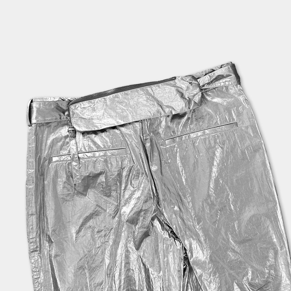 A pair of shiny silver pants with a belt and zipper.