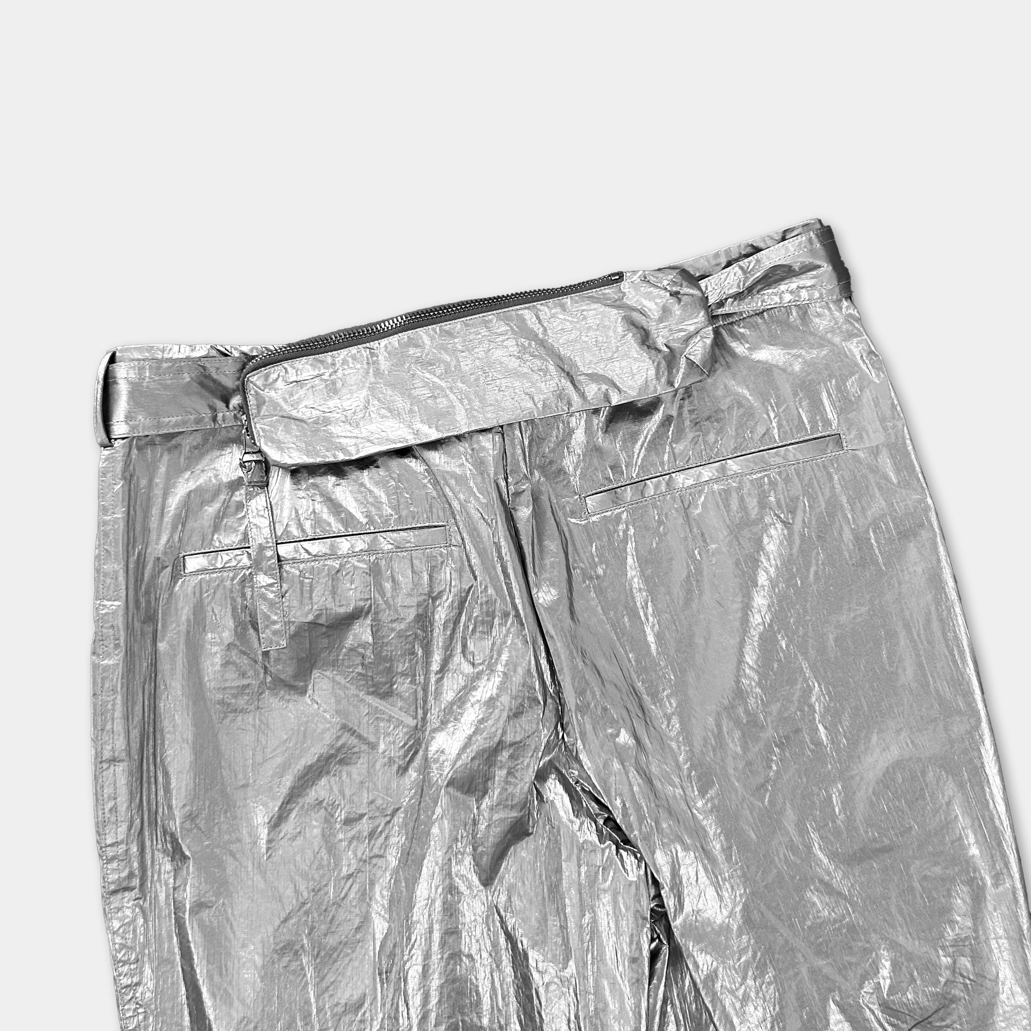 A pair of shiny silver pants with a belt and zipper.
