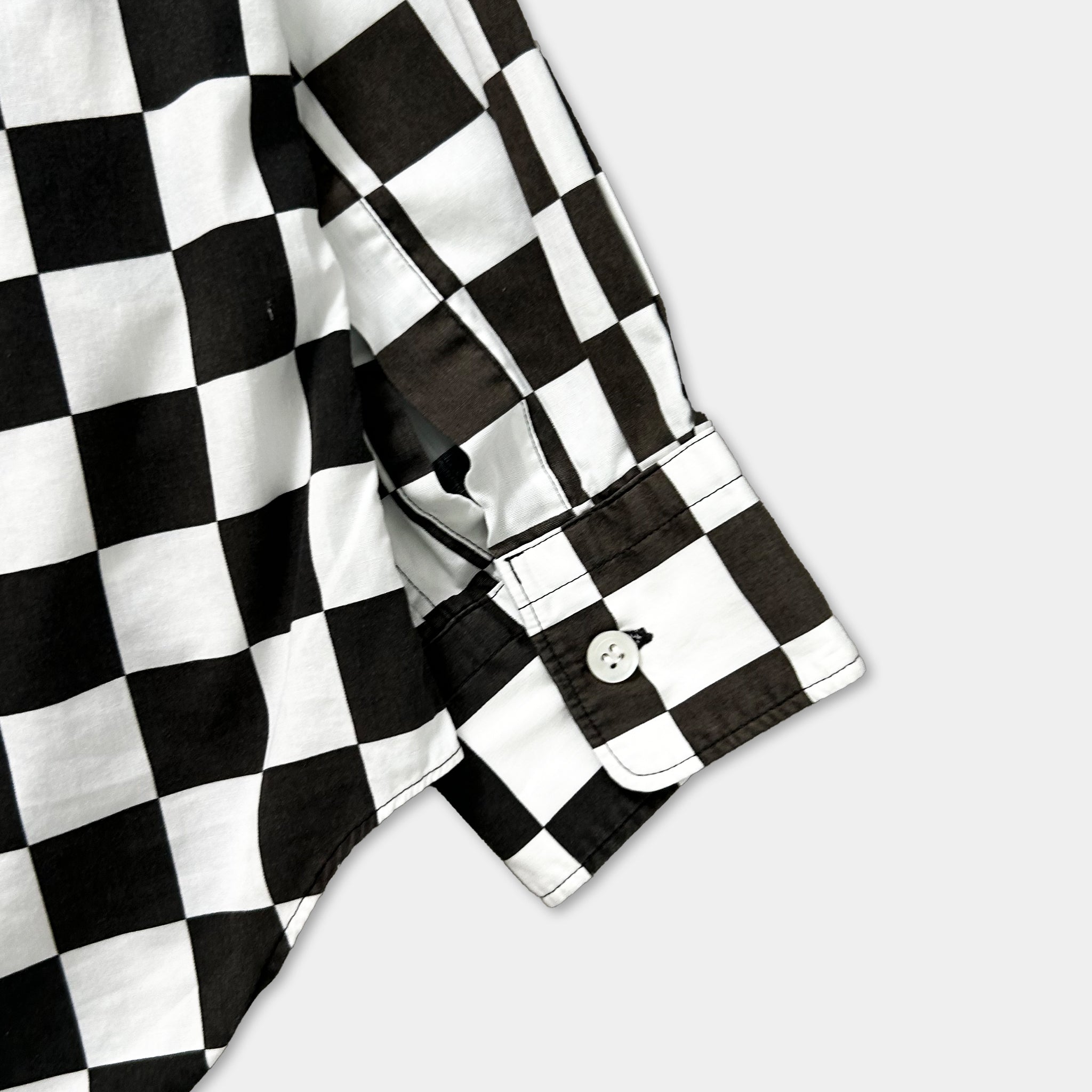 a close-up view of a black and white checkered shirt, with the sleeves and collar visible.