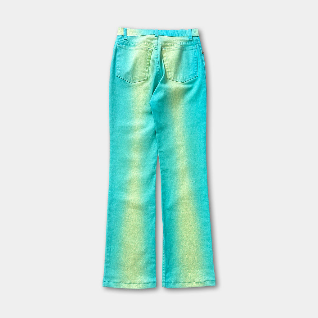 A pair of turquoise-colored jeans with a faded green gradient, displayed against a plain white background.