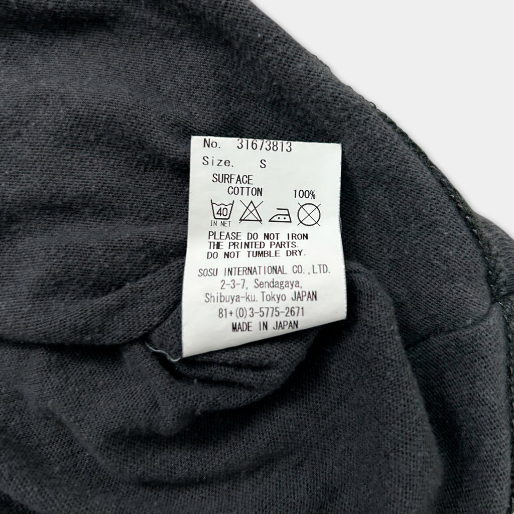 a close-up view of a grey fabric, possibly a piece of clothing, with a label attached to it. The label provides information about the fabric, such as its size and material, and includes a washing instructions.