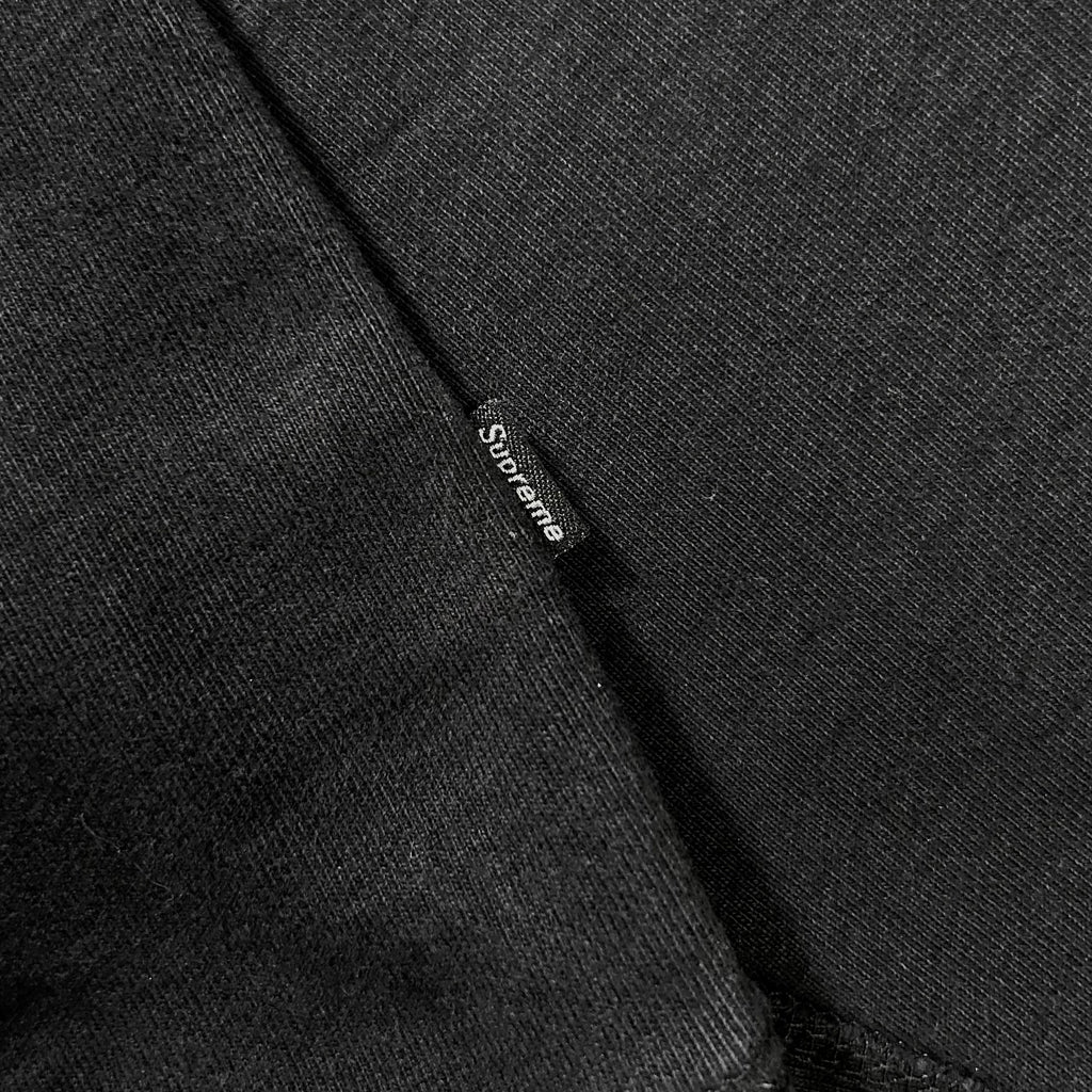 A close-up view of a black fabric, possibly a shirt or garment, with a small white label or tag attached to it.